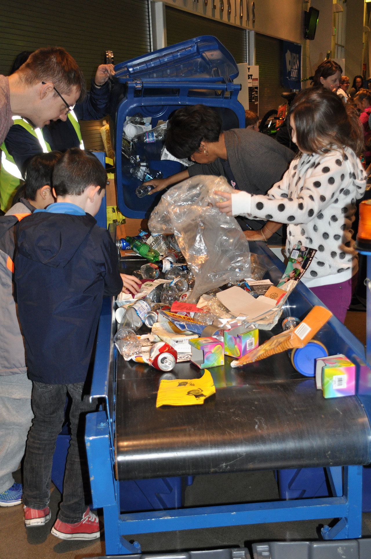 Children sort recyclable items from garbage at the Republic Services booth during the You Me We festival last Friday at Kent’s ShoWare Center. HEIDI SANDERS, Kent Reporter
