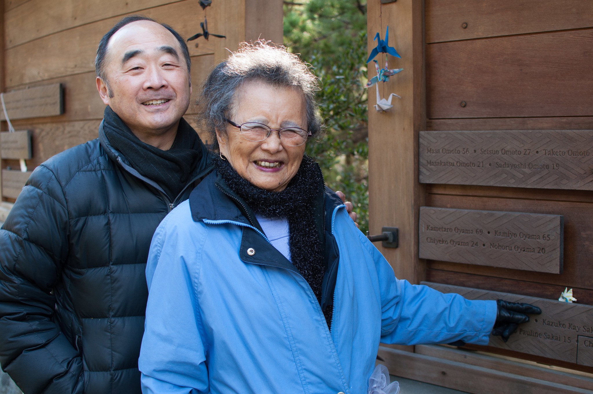 Kay Sakai points at her name on the Bainbridge Island Japanese American Exclusion Memorial, which includes the name of every Japanese American resident of the island removed under Civilian Exclusion Order No. 1. Behind her stands Clarence Moriwaki, founder of the Bainbridge Island Japanese American Exclusion Memorial. Photo by Enrique Pérez de la Rosa, WNPA Olympia News Bureau