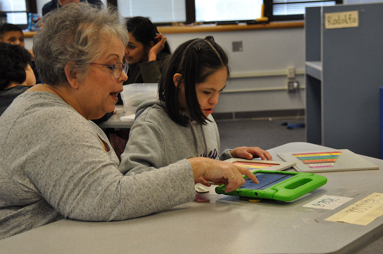 Jackie DeCamp, a paraeducator in the Adaptive Support Center at Cedar Heights Middle School, helps Melissa use her iPad to communicate. HEIDI SANDERS, Kent Reporter