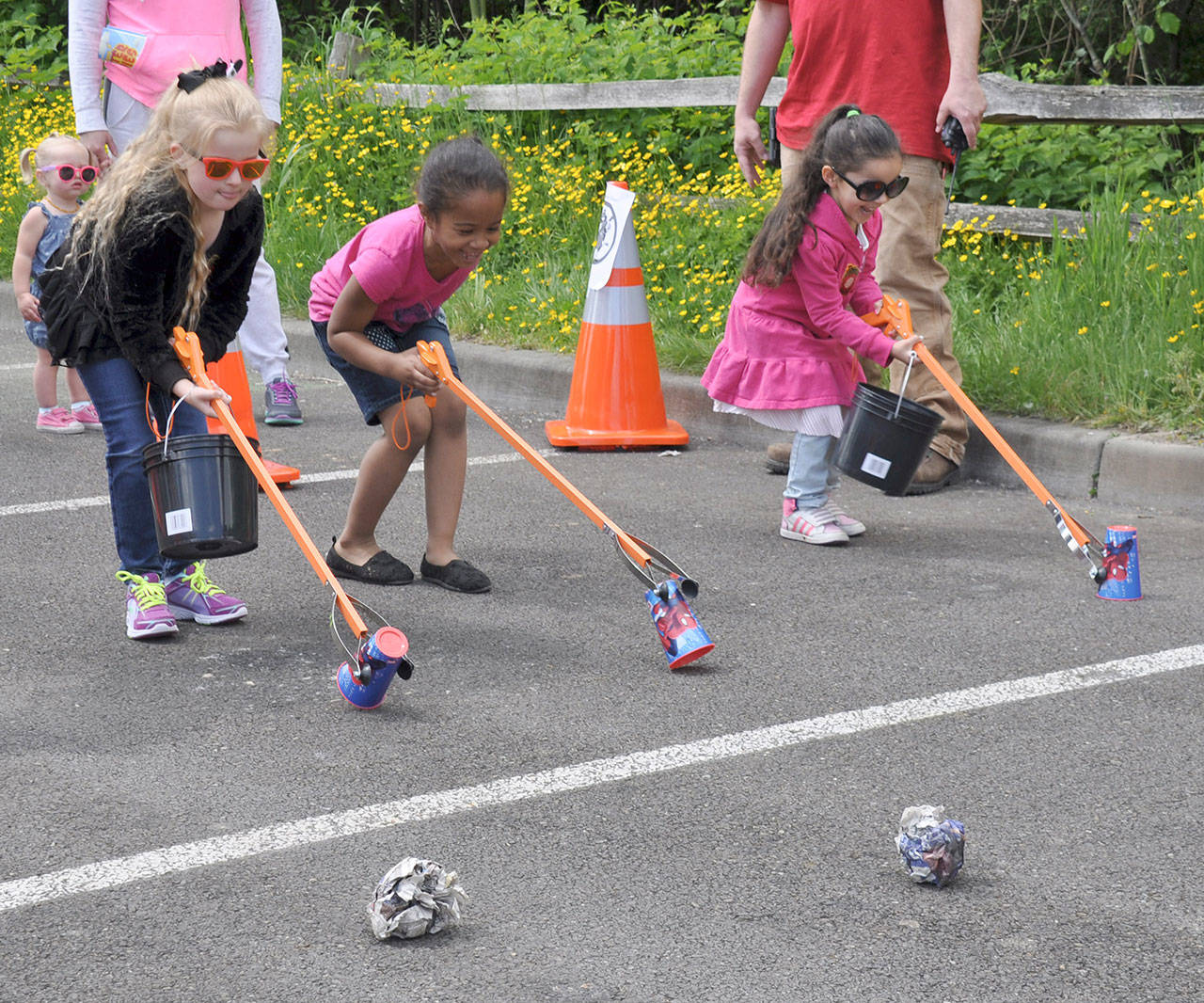 From left, Lauren Law, 6, Leilani Goodnow, 5, and Naomi Goodnow, 5, all of Kent, pick up cups during a garbage collection race. HEIDI SANDERS, Kent Reporter
