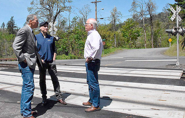 Gov. Jay Inslee, left, BNSF Railway spokesman Gus Melonas and state Utilities and Transportation Commission Chairman David Danner discuss improvements to the railroad crossing near Butler Loop Road in Skamania County during a visit Tuesday by Inslee to the crossing.