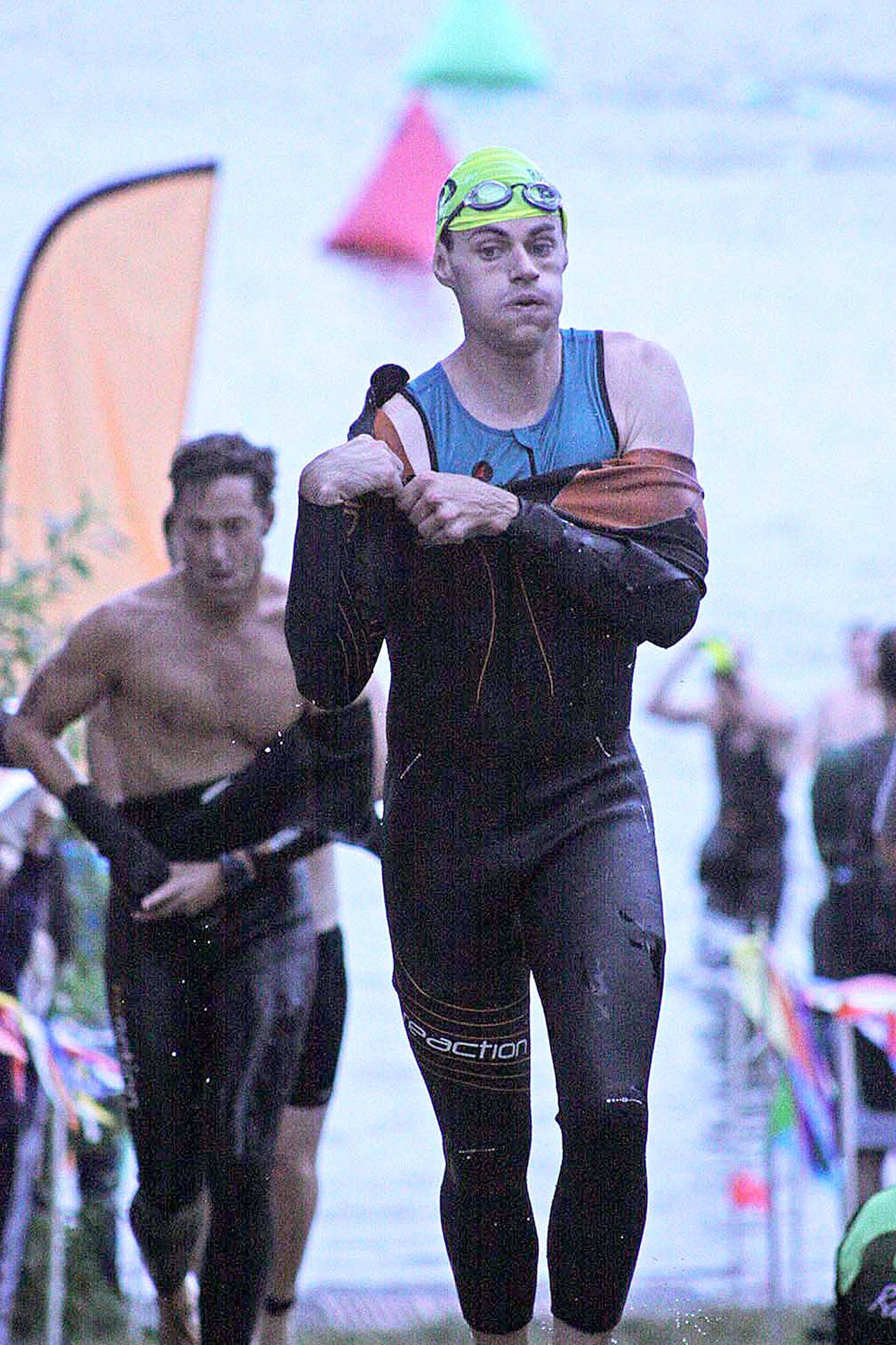 Andrew Richards, who finished second in the men’s sprint wave division, tries to shed his wet suit after leaving the Lake Meridian waters in the opening swim segment en route to the transition area for the bike leg. MARK KLAAS, Kent Reporter