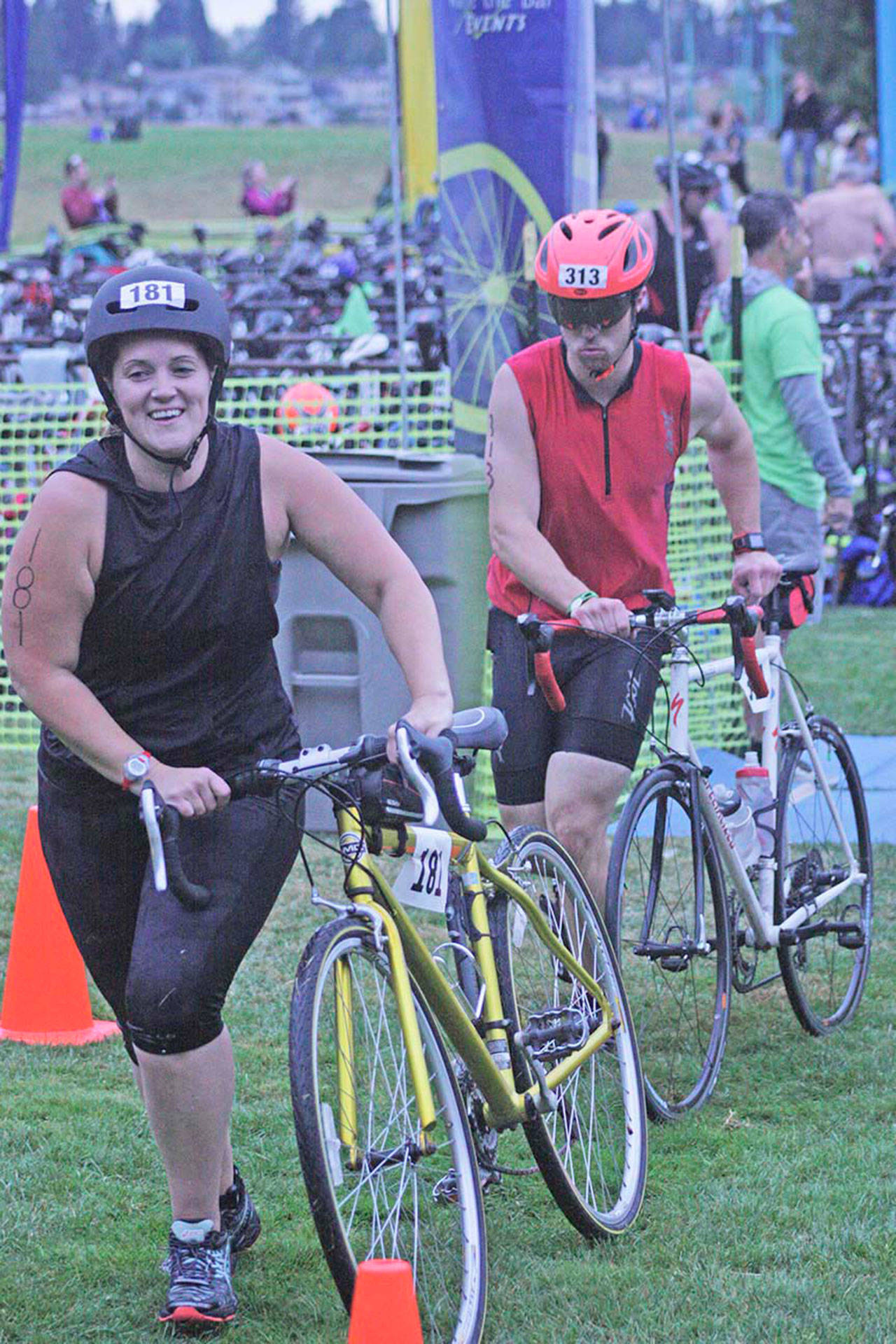 Lydia Fenton, left, and Daniel Neumann, roll their bikes from the transition area during the Lake Meridian Triathlon. MARK KLAAS, Kent Reporter