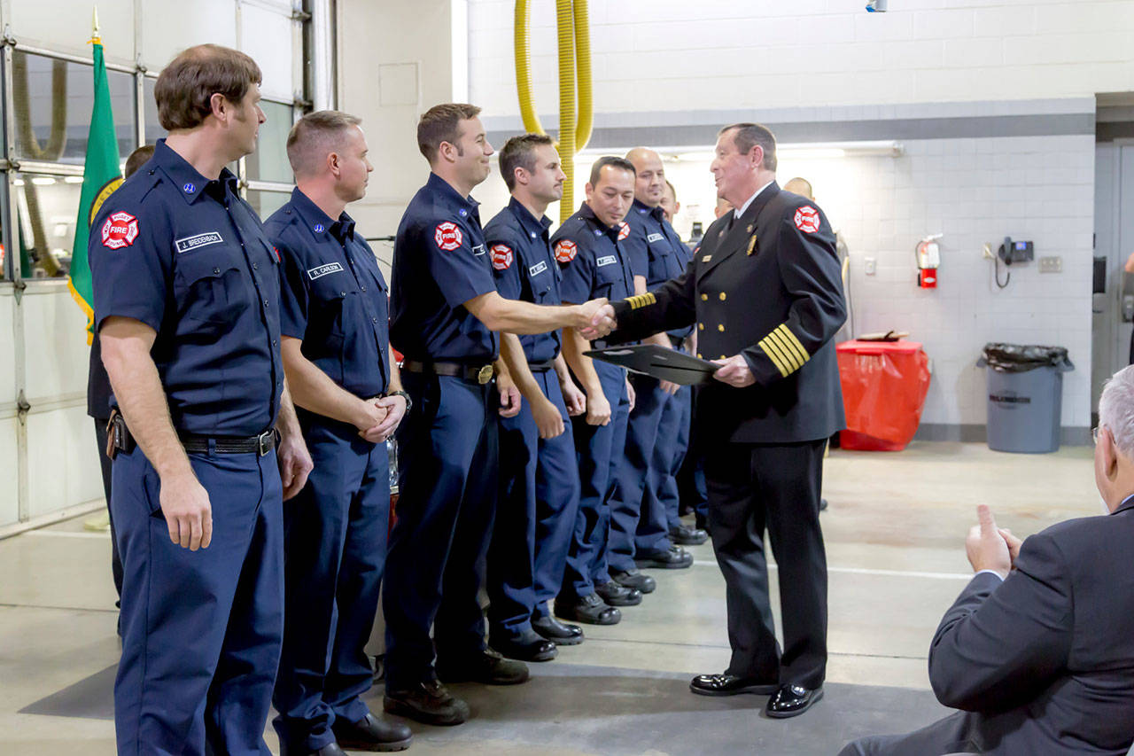 Jim Schneider, right, congratulates a group of captains after swearing them in. Schneider retired as chief of the Puget Sound Regional Fire Authority on Aug. 30 after a more than 40-year career in fire service. COURTESY PHOTO