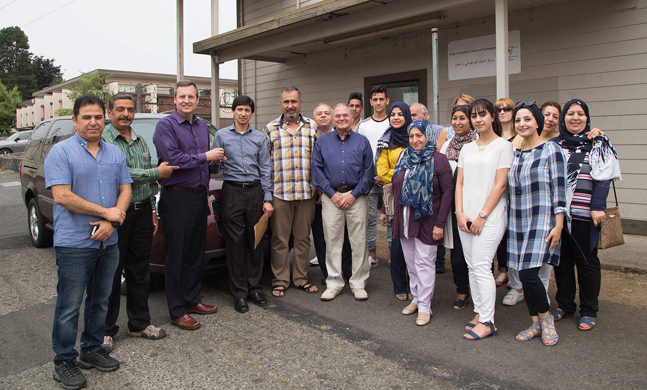 Surrounded by clients and staff from the Iraqi Community Center of Washington, King County Council member Dave Upthegrove presents the keys to a retired King County vanpool van to Yahya Algarib, Executive Director of the Community Center. COURTESY PHOTO, King County