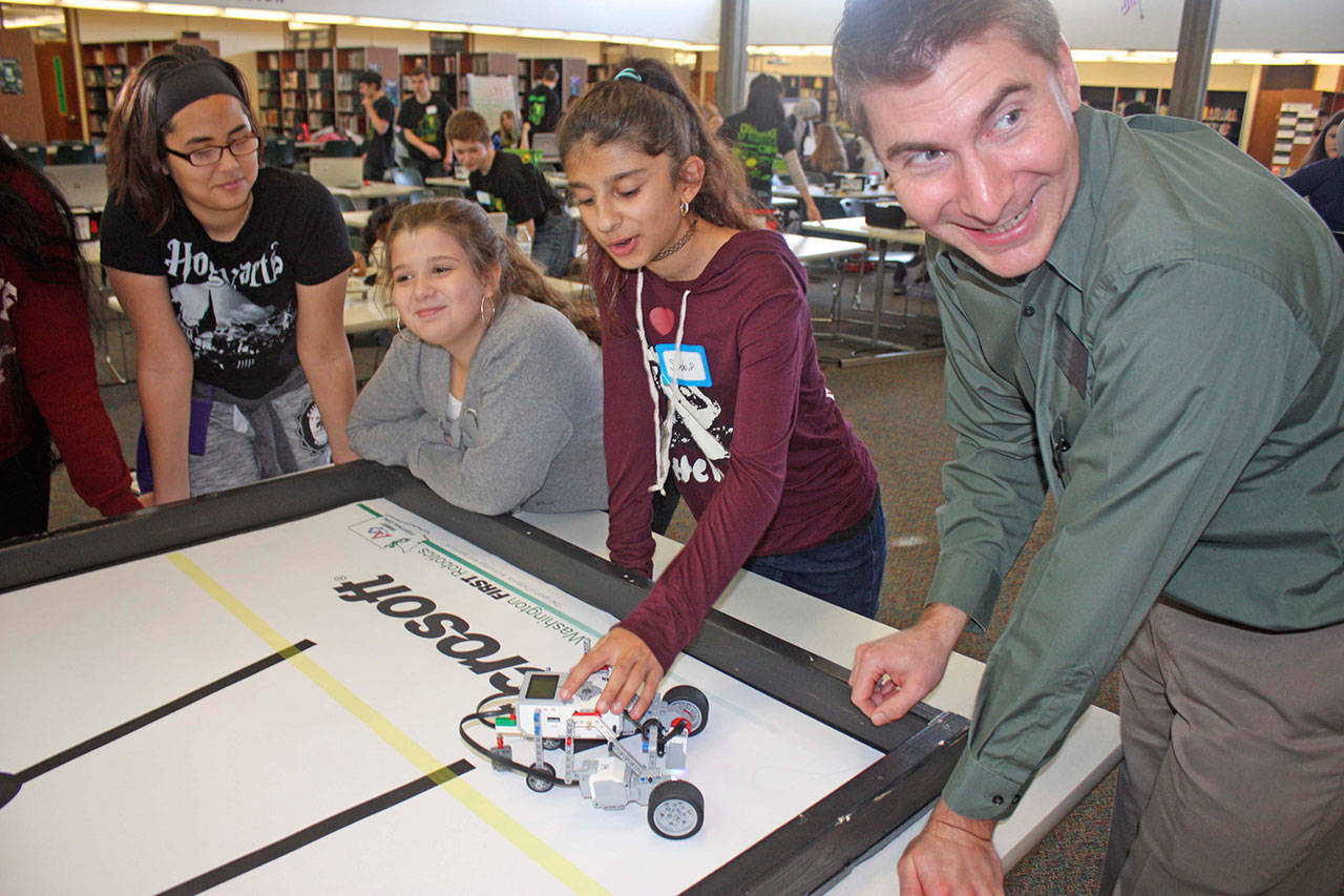 The Kent Chamber of Commerce’s Byron Ford, who is part of the chamber’s Green River College education committee, works with students in the Kentridge High School library at the STEM field-trip event for middle school girls on Monday. MARK KLAAS, Kent Reporter