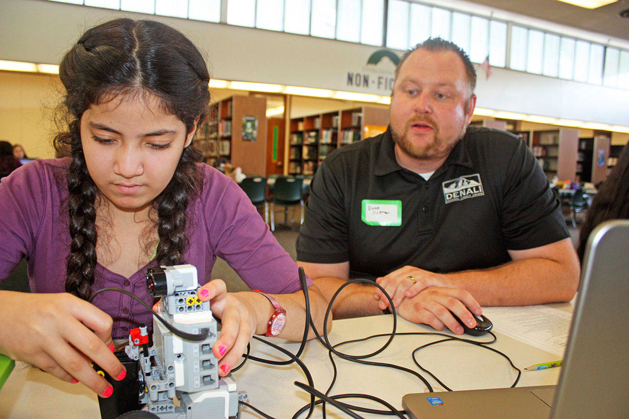 Derek Dykman, a business banker with Denali Federal Credit Union, oversees the robotic work of Fatema Metwally, an eighth-grader at Meridian Middle School, in the Kentridge High School library at the STEM event for girls on Monday. MARK KLAAS, Kent Reporter