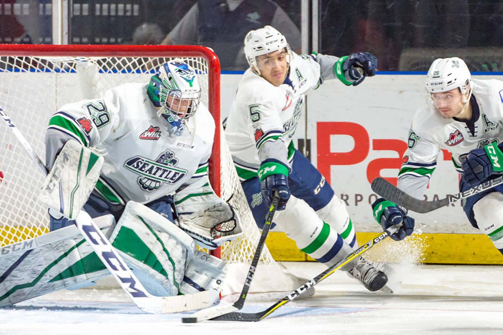 The Thunderbirds’ Jarret Tyszka, middle, and Nolan Volcan, right, reach to push the puck away from goalie Matt Berlin during WHL play against Spokane on Friday night. COURTESY PHOTO, Brian Liesse, T-Birds