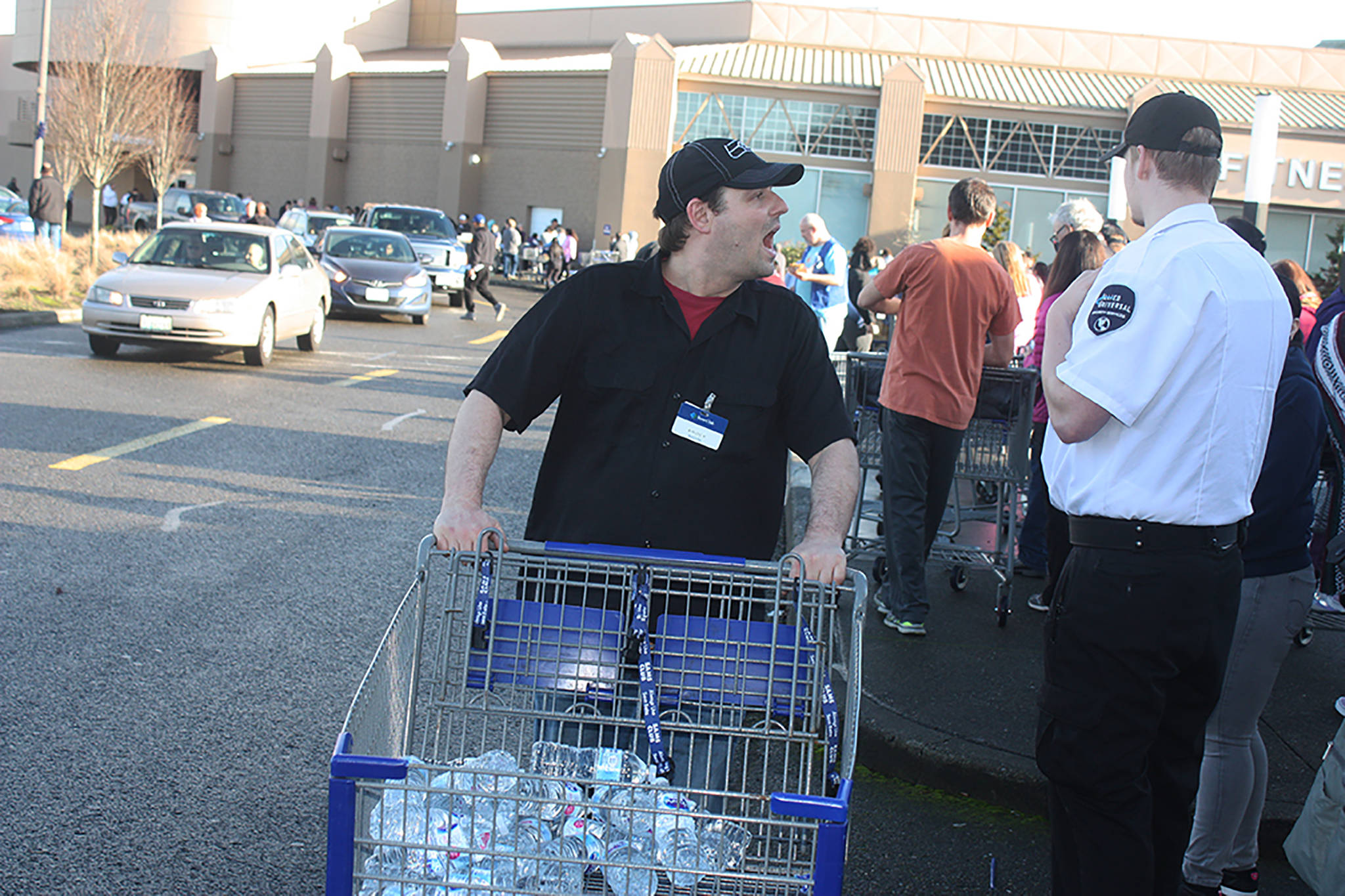 A Sam’s Club employee shouts to offer water to customers waiting patiently and long to enter the store on Saturday afternoon. The line stretched along one side of The Outlet Collection mall in Auburn, with patrons waiting an hour to an hour and a half to enter the bargain-selling store that’s scheduled to close Jan. 26. MARK KLAAS, Reporter