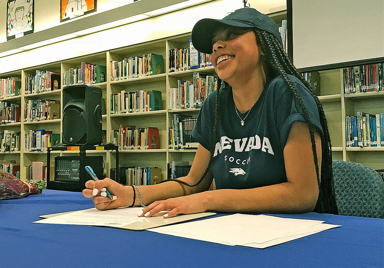 Kent-Meridian High School senior Olivia Carter breaks into a smile as she signs her national letter on intent to attend and play soccer at the University of Nevada during a ceremony Wednesday at the school library. MARK KLAAS, Kent Reporter