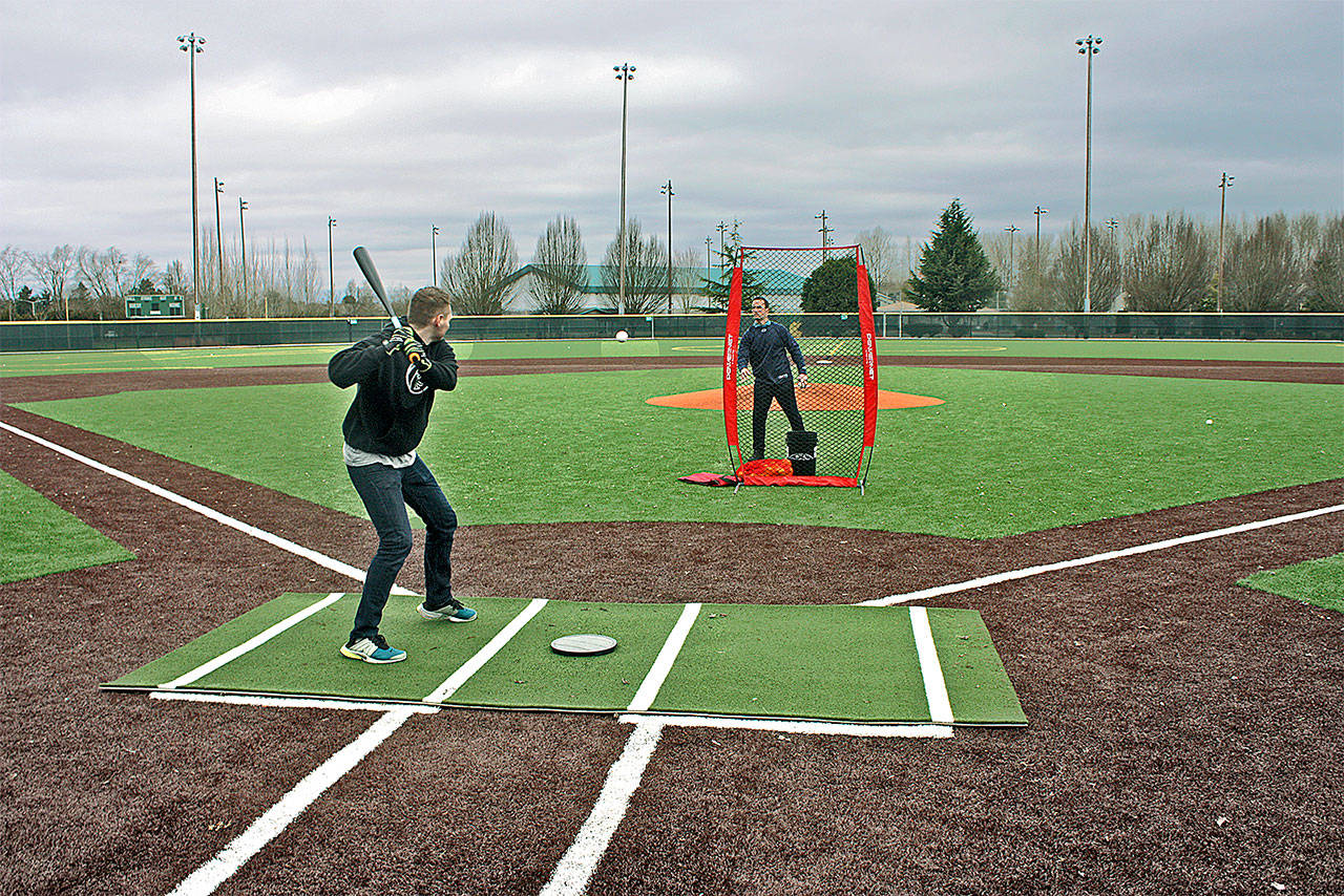 Representatives from Axe Bat try out the newly resurfaced main baseball field at Hogan Park at Russell Road on Tuesday. The city converted the main field at the park, 24400 Russell Road, to synthetic turf from grass for year-round use. Kent city officials will celebrate the improvements at a grand re-opening March 10. MARK KLAAS, Kent Reporter