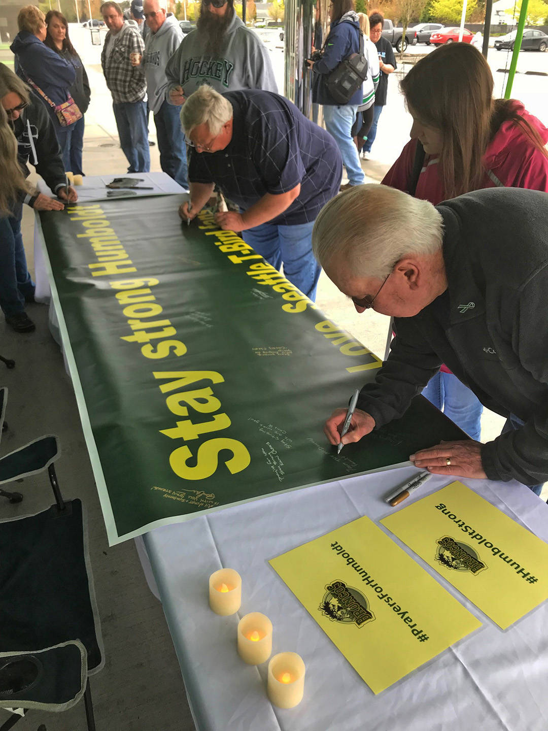 Bruce McDonald, foreground, and his 15-year-old daughter, Chloe, join others outside the accesso ShoWare Center on Saturday in signing a banner supporting the Humboldt, Saskatchewan junior hockey team. MARK KLAAS, Kent Reporter