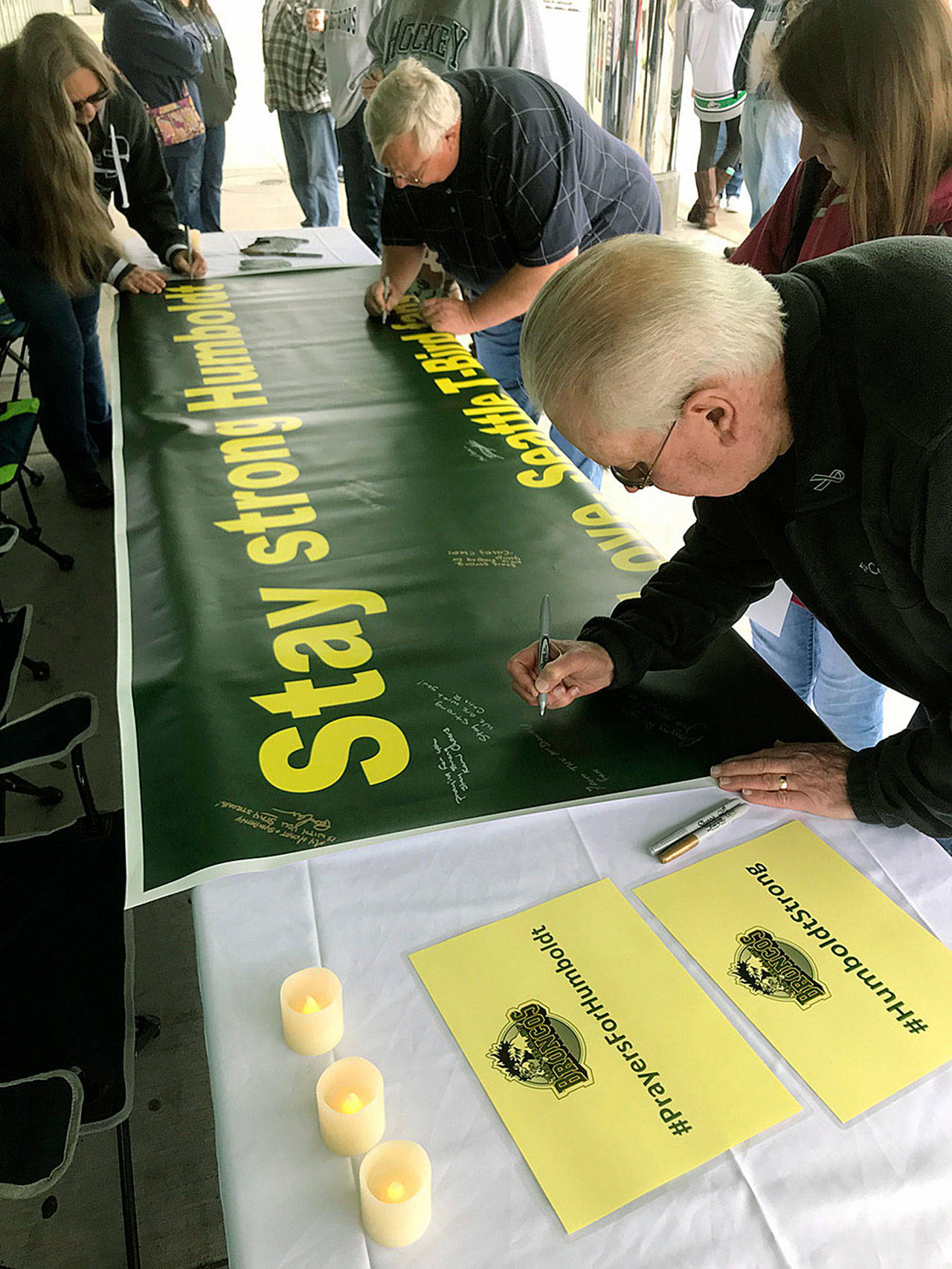 Bruce McDonald, foreground, and his 15-year-old granddaughter, Chloe, join others outside the accesso ShoWare Center last Saturday in signing a banner supporting the Humboldt, Saskatchewan junior hockey team. MARK KLAAS, Kent Reporter
