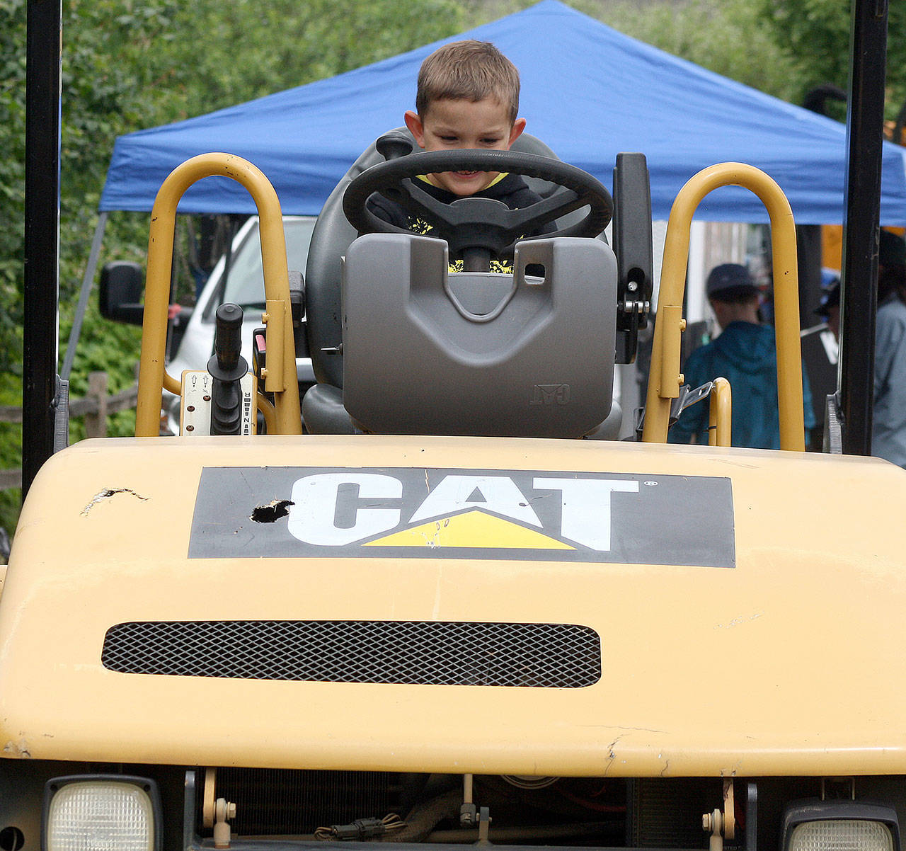 Karston Jenkins, 4, of Milton, takes a seat in an asphalt roller during the annual City of Kent Public Works Department demonstration day at the accesso ShoWare Center on Thursday. Jenkins attended the event with his mother and his grandmother, who lives in Kent. The event gives people a chance to see what Public Works employees do for the city. STEVE HUNTER, Kent Reporter