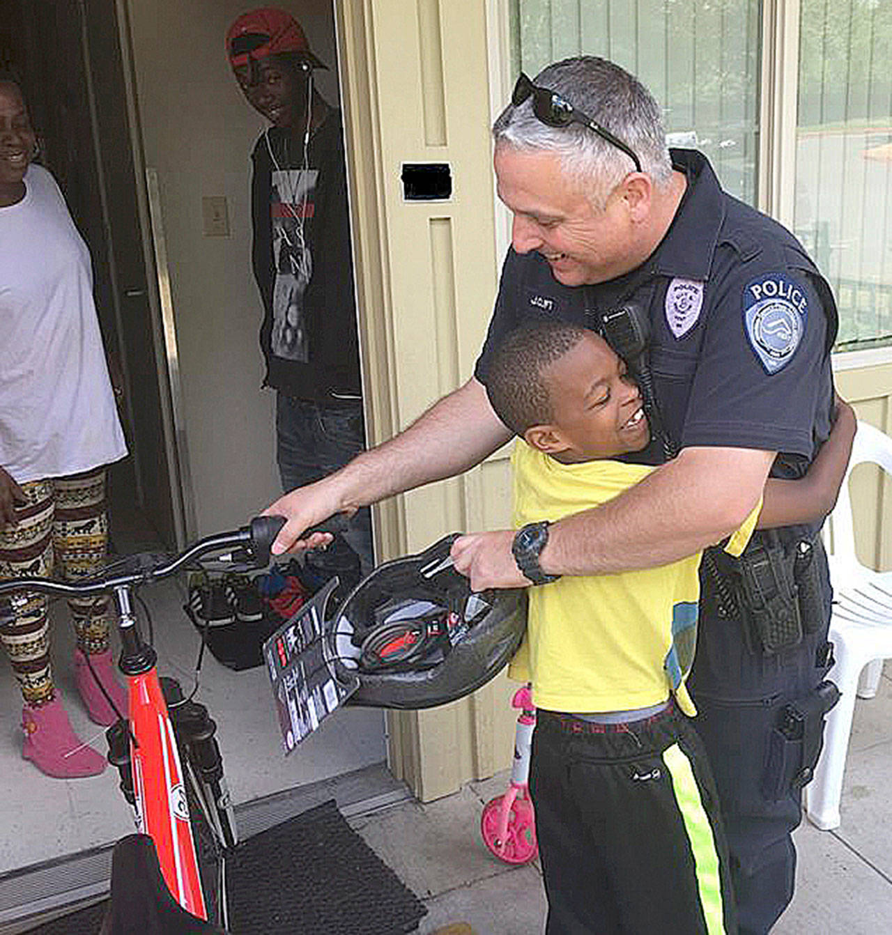 Kent Police Officer Jason Clift gets a big hug after delivering a new bicycle to a Kent boy. COURTESY PHOTO, Kent Police