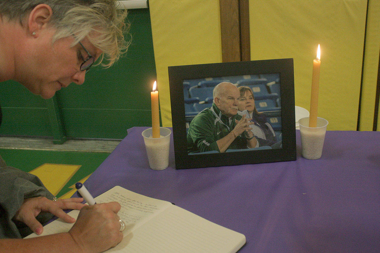 Carrie Lantz signs a memorial book before the start of a candlelight vigil for Kentridge’s longtime athletic director Eric Anderson, who died Saturday at age 57. MARK KLAAS, Kent Reporter