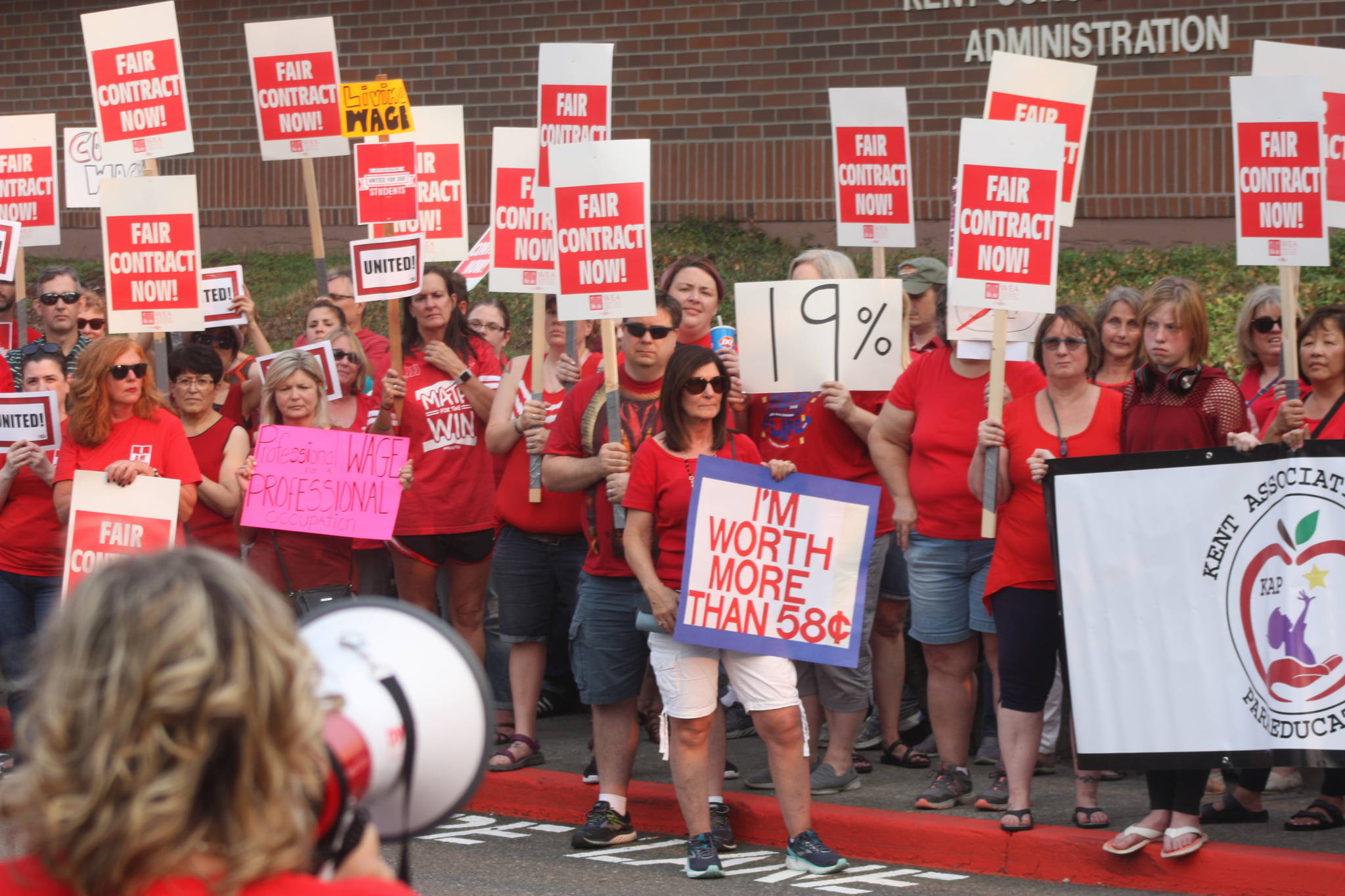 Maureen DeBoo-Cahoon, on the magaphone, leads members of the Kent Association of Paraeducators at a rally outside school district offices Wednesday. MARK KLAAS, Kent Reporter