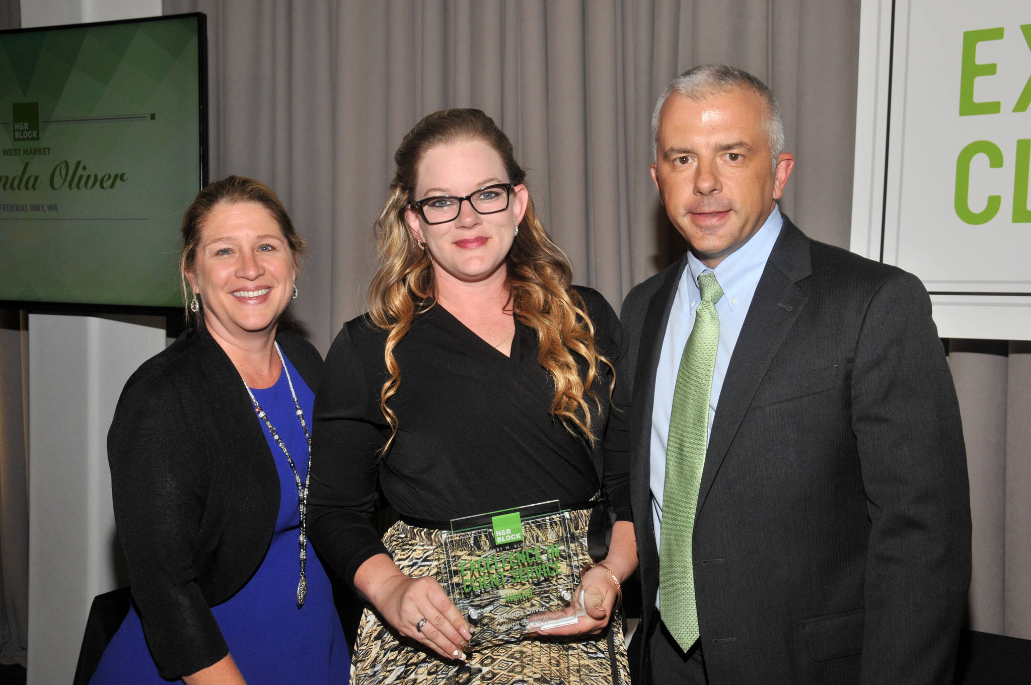 Diane Cooley, H&R Block vice president of retail and sales, left, and Tim Rush, H&R Block vice president of field operations, present Amanda Oilver with the Henry W. Bloch Excellence in Client Service award. COURTESY PHOTO