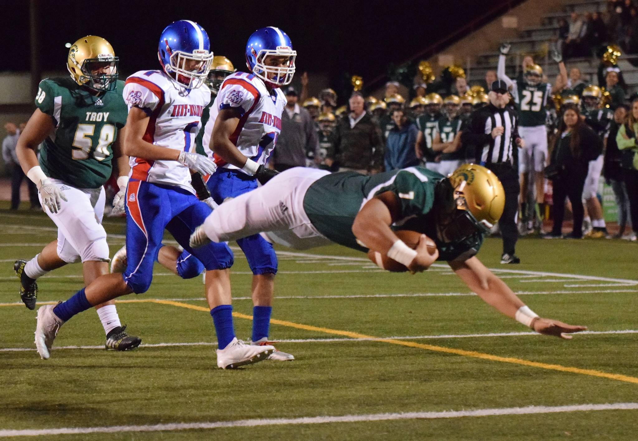 Auburn quarterback Calvin Liulamaga dives into the end zone, scoring one of his two first-half touchdowns against Kent-Meridian on Friday night. Pursuing are the Royals’ Ronald Wilson, left, and Nate Jones. Liulamaga accounted for four TDs as the Trojans prevailed 43-35 in a North Puget Sound League interdivisional game. RACHEL CIAMPI, Auburn Reporter