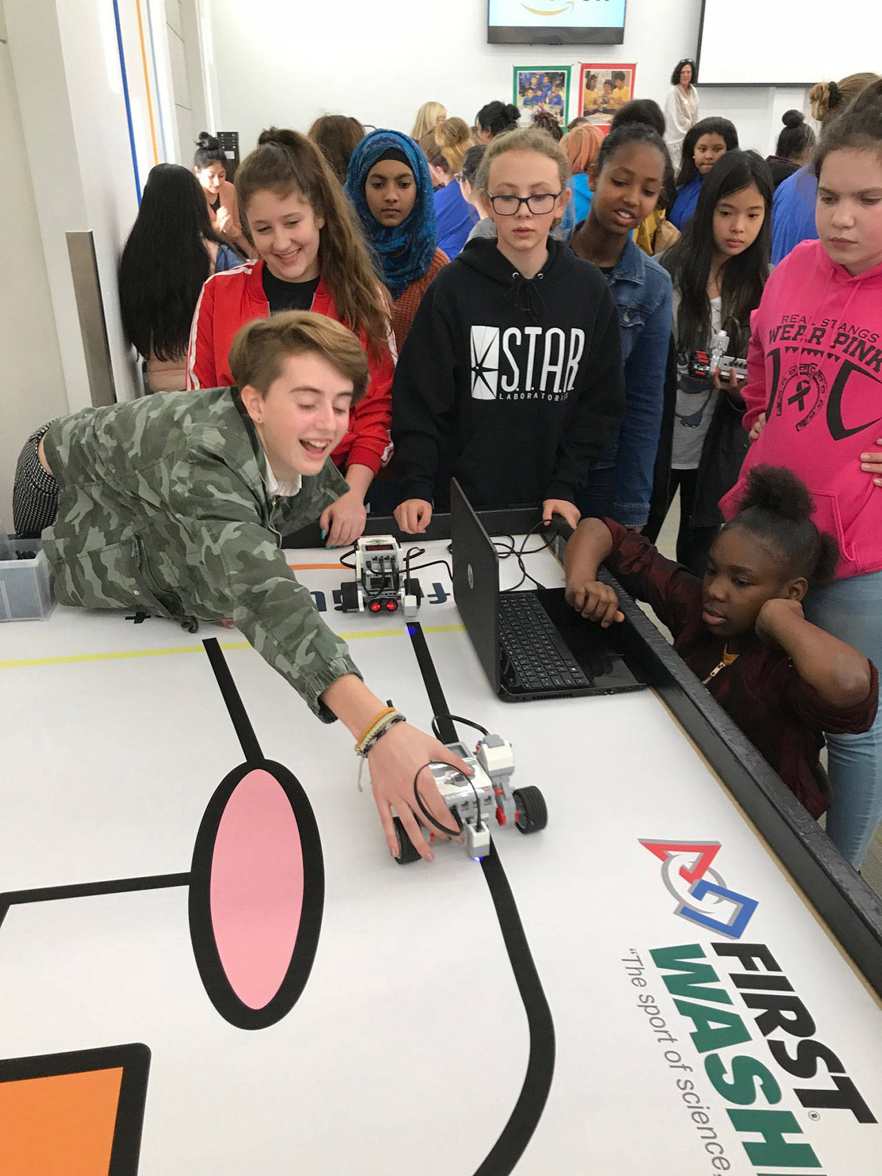 Serra McMurray, a Mattson seventh-grader, reaches for her team’s robot after doing a run during the STEM event Tuesday. MARK KLAAS, Kent Reporter