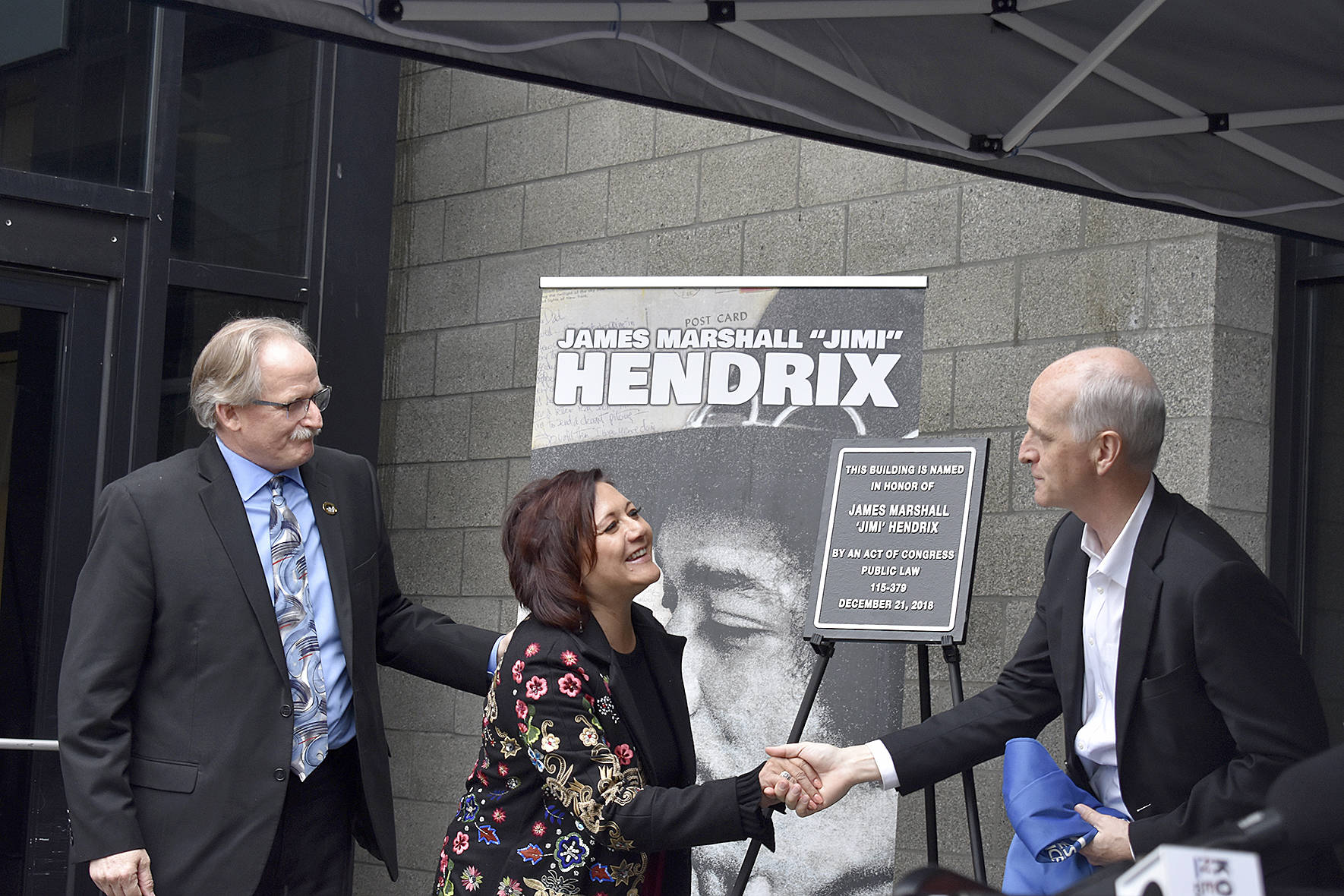 USPS district manager Darrell Stoke, Janie Hendrix and Congressman Adam Smith (D-WA) unveil the plaque honorarily naming the Renton Highlands Post Office as the “James Marshall ‘Jimi’ Hendrix Post Office” on Friday, April 19. Photo by Haley Ausbun