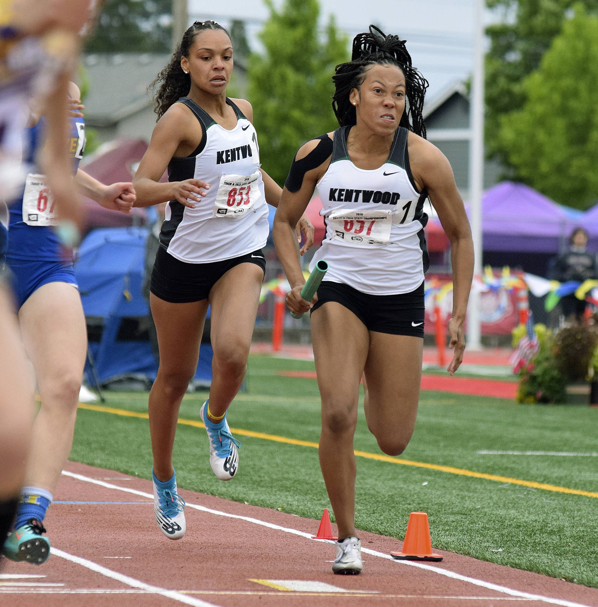 Faith Marshall passes the baton to Makayla Williams during Kentwood’s 800-meter relay victory at the rain-soaked state track and field championships at Mount Tahoma High School in Tacoma last Saturday. RACHEL CIAMPI, Kent Reporter