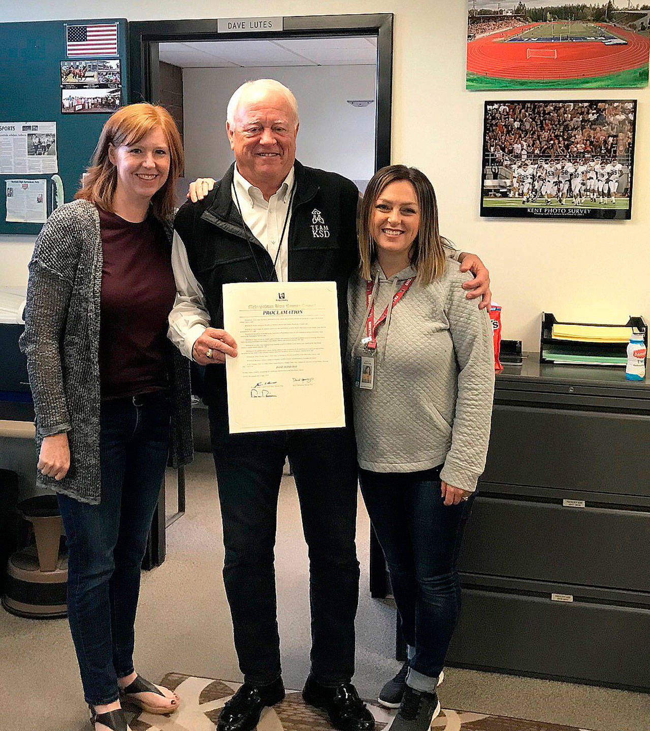 Amy Erickson, Dave Lutes and Holly Potts with the Kent School District join Lutes as he holds the proclamation from the King County Council declaring June 7 as ‘Dave Lutes Day.’ Lutes retired Friday after 42 years with the district as a teacher, coach and athletic director. COURTESY PHOTO, King County