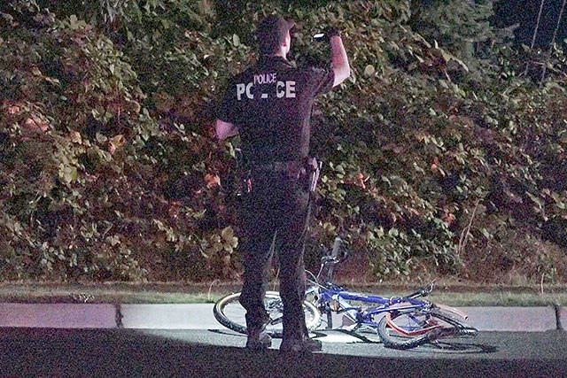 A police officer stands near the bike that was struck during a hit-and-run that killed a 34-year-old man in Federal Way on Friday. COURTESY PHOTO, Evergreen Media Production