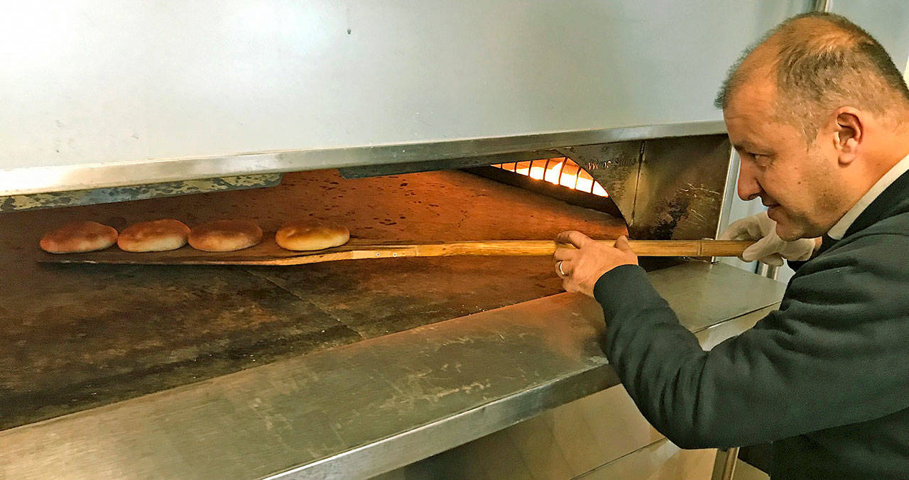 Mehmet Sipahioglu, owner and chef of Mediterranean Breeze Wood Fired Restaurant, tends to bread baking in the oven. MARK KLAAS, Kent Reporter