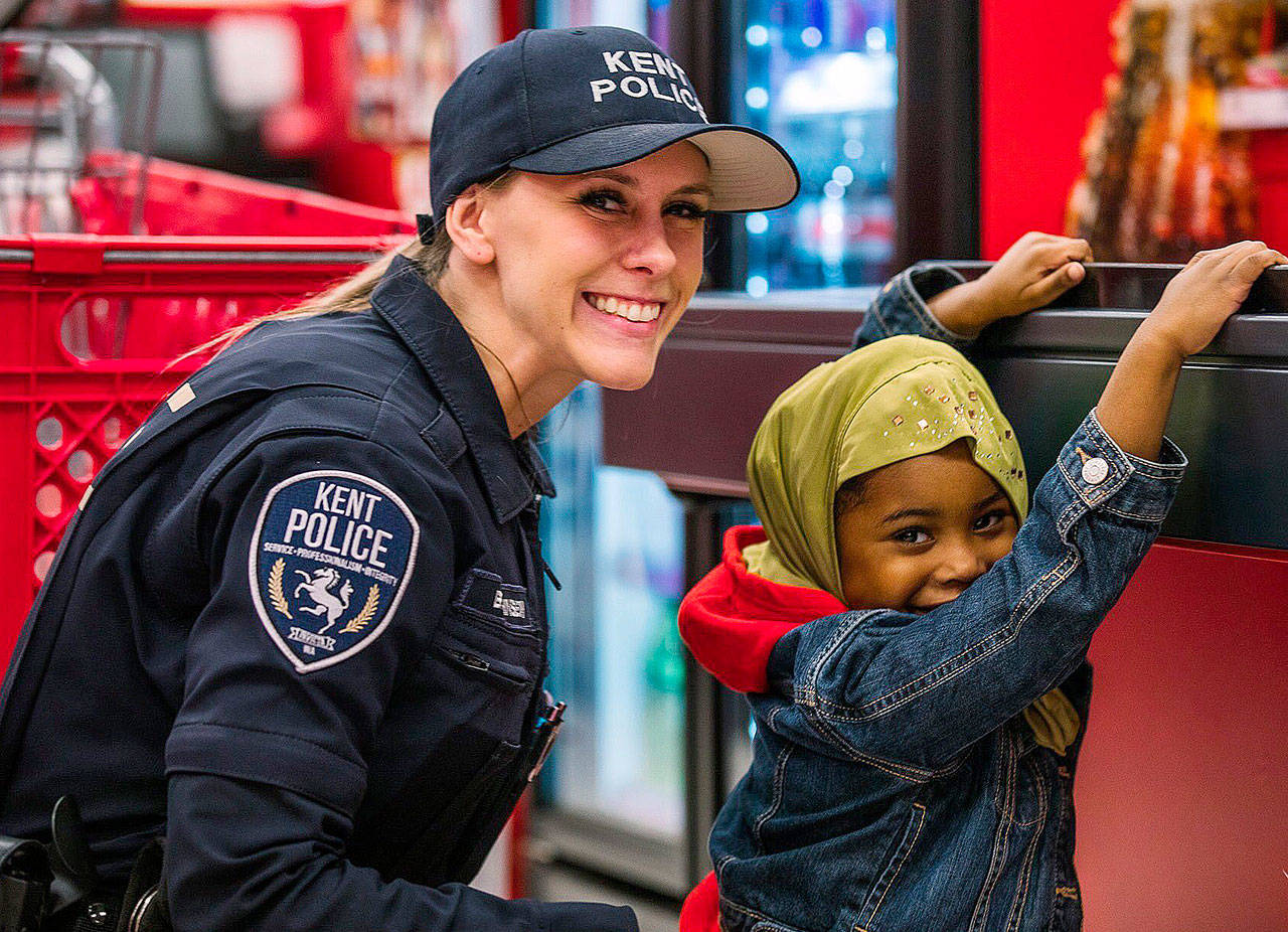 A Kent Police officer poses with a child at the Heroes & Helpers (shop with a cop) event. Dec. 7 at Target. COURTESY PHOTO, City of Kent