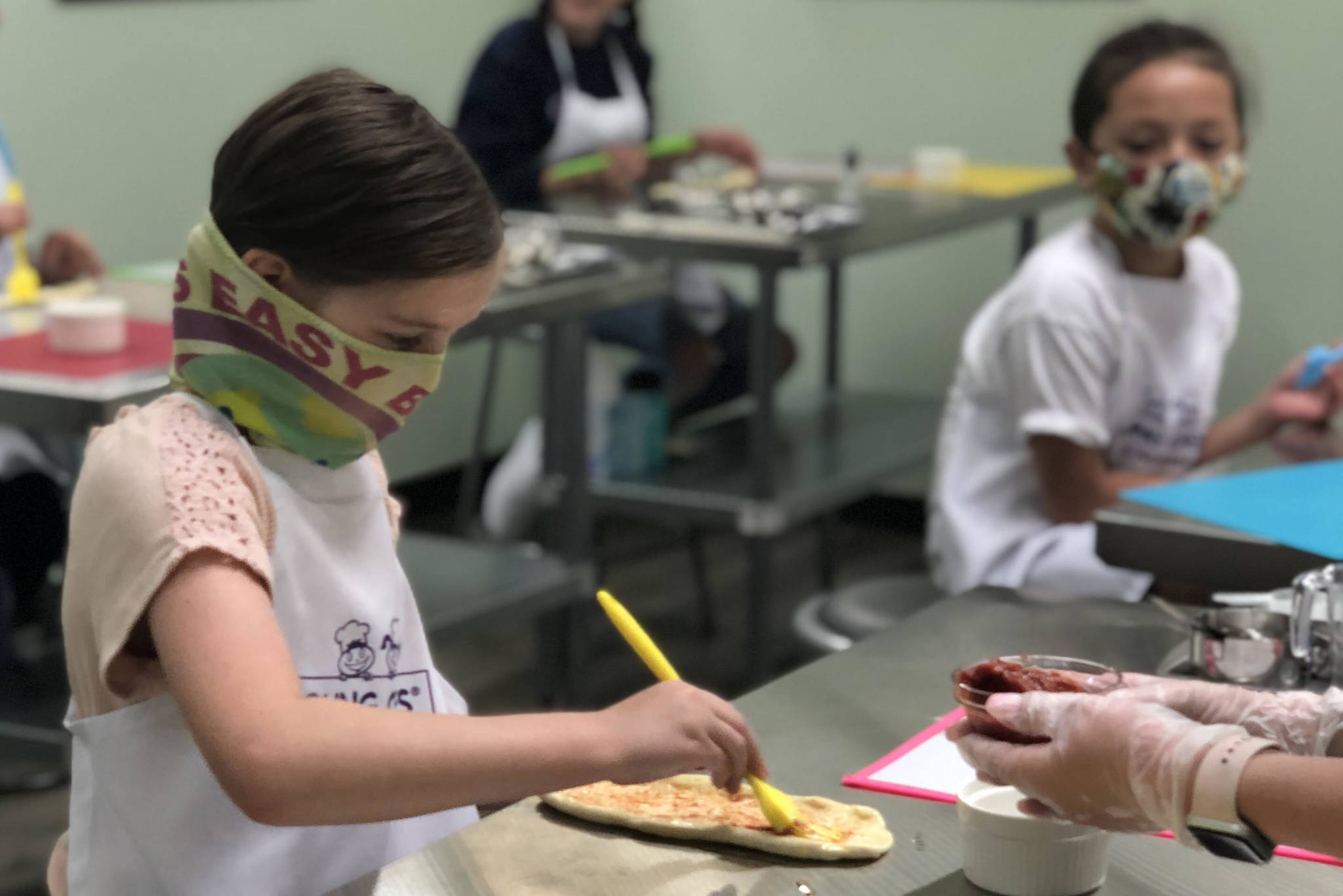 A young chef carefully spreads sauce onto pizza dough during a cooking class at Young Chefs Academy of Covington. Courtesy photo/YCA Covington