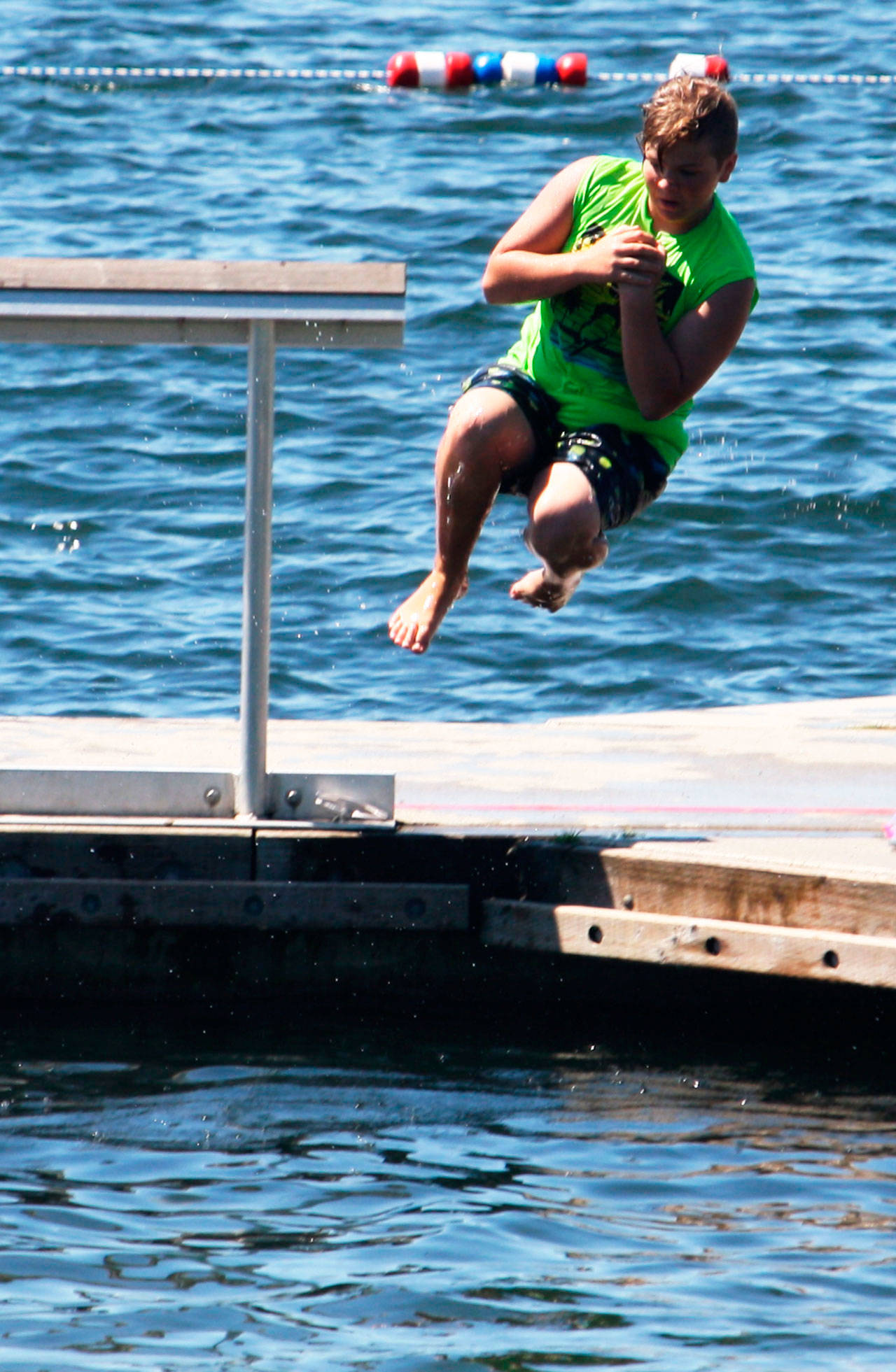 A boy jumps off the dock Monday at Lake Meridian. STEVE HUNTER, Kent Reporter