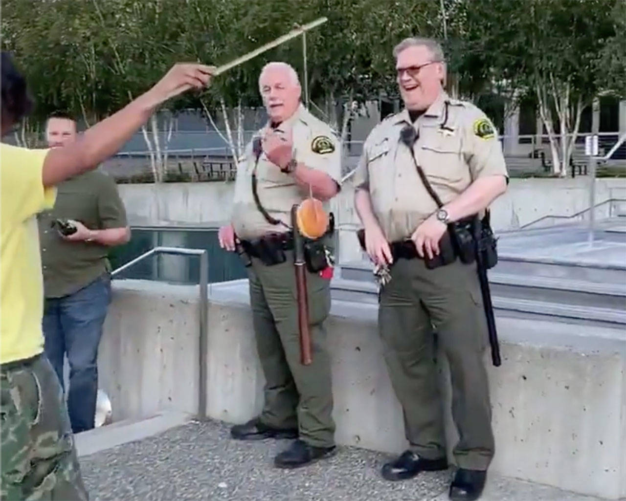 A man dangles a doughnut in front of police officers. (Screen grab from video courtesy of Bennett Haselton)