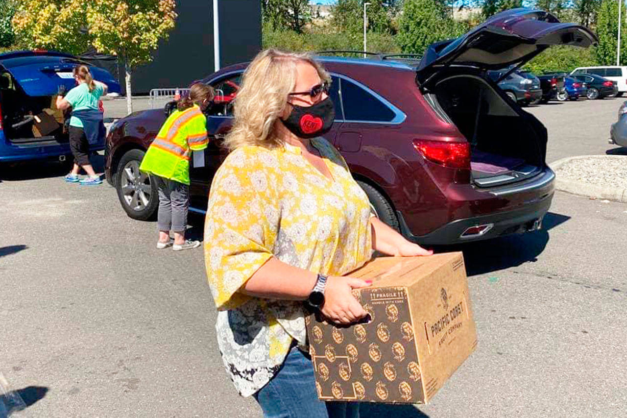 Kent Mayor Dana Ralph delivers a box of food during a free distribution of food, face masks and hand sanitizers on Aug. 28 at the accesso ShoWare Center. COURTESY PHOTO, City of Kent