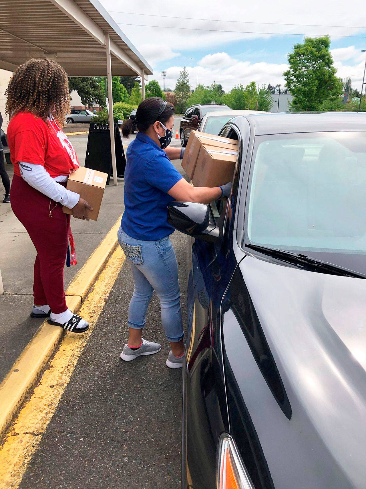 Volunteers deliver a food box to a vehicle during a Kent School District distribution day. COURTESY PHOTO, Kent School District