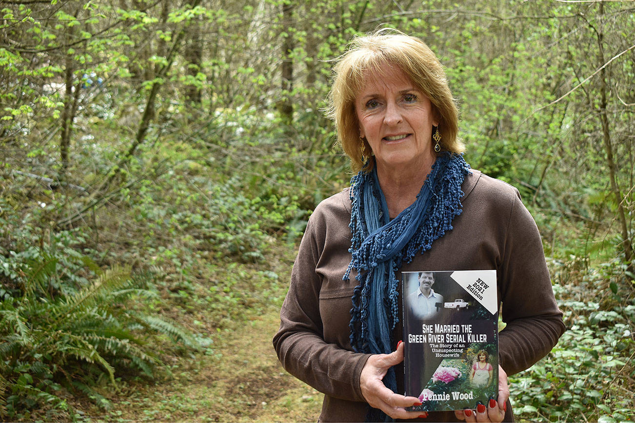 Penny Wood holds a copy of her book “She Married The Green River Serial Killer” on a trail near her Ravensdale home April 28. Photo by Alex Bruell