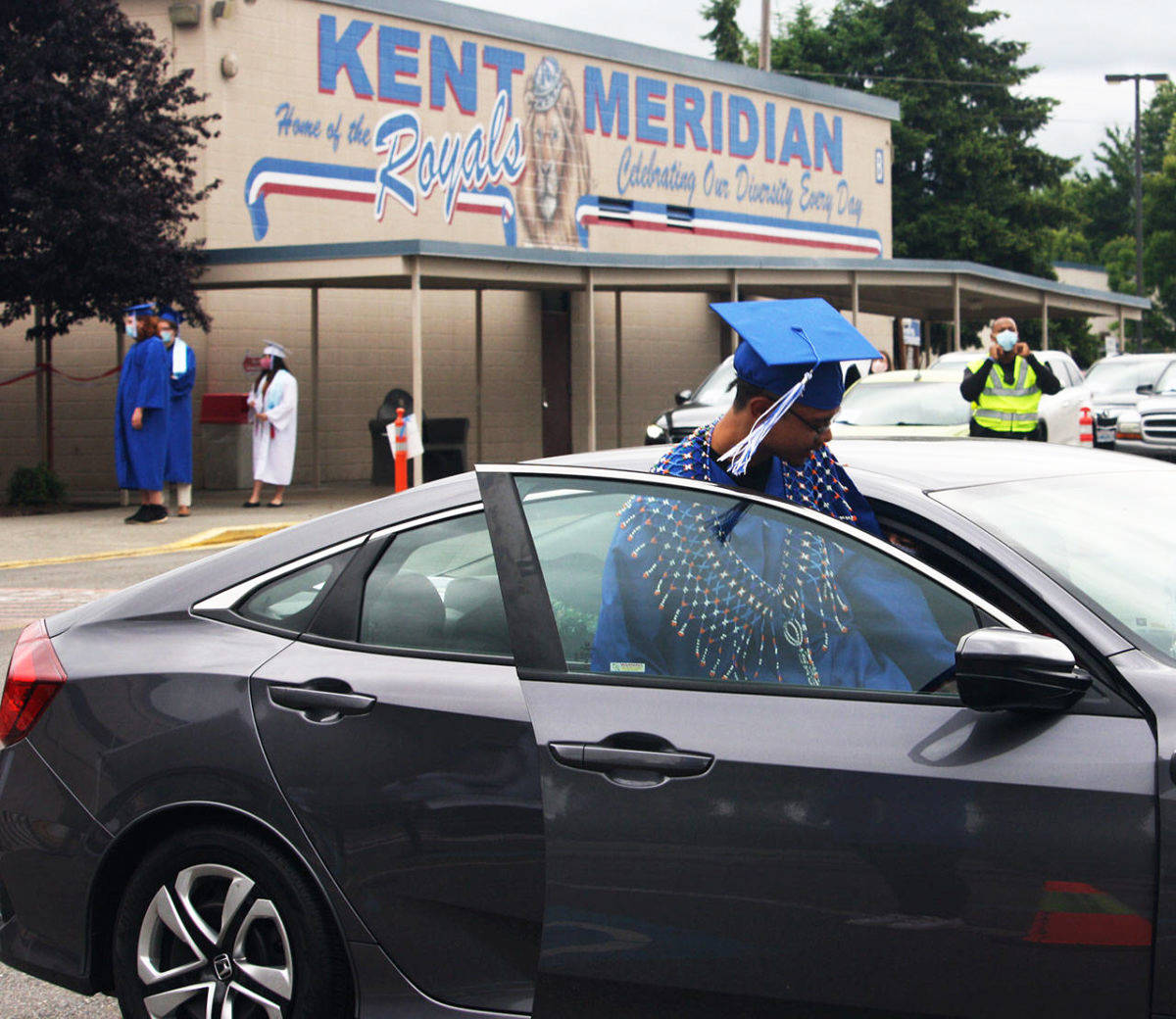 A Kent-Meridian High graduate jumps in a car after receiving his diploma during a 2020 ceremony outside the school. FILE PHOTO, Kent Reporter