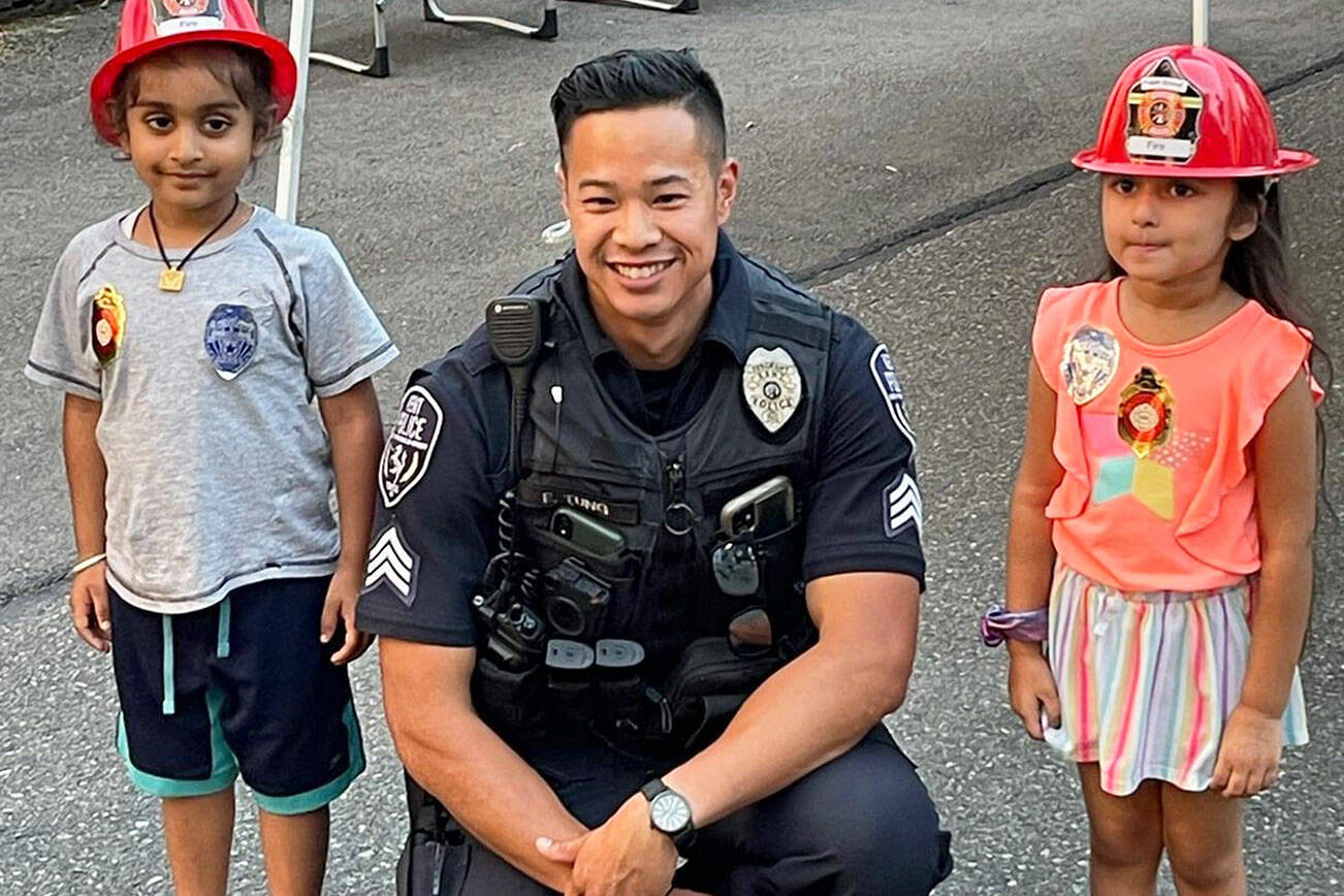 Kent Police Sgt. Eric Tung poses with a couple of children during a 2021 National Night Out event. COURTESY PHOTO, Kent Police