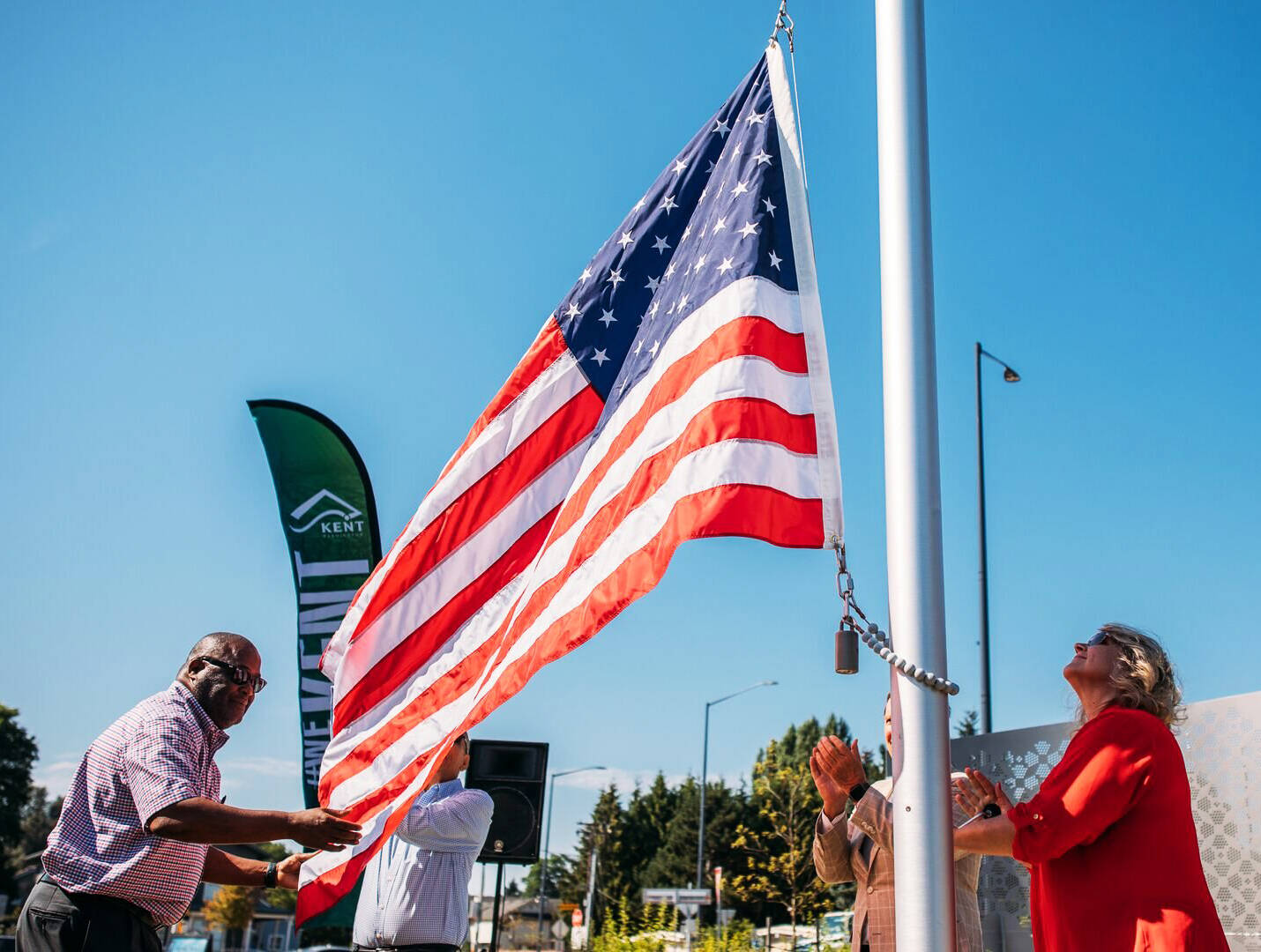 Kent City Council President Bill Boyce and Mayor Dana Ralph raise the American flag at a new pole installment at the Fourth Avenue South and Willis Street roundabout. COURTESY PHOTO, City of Kent