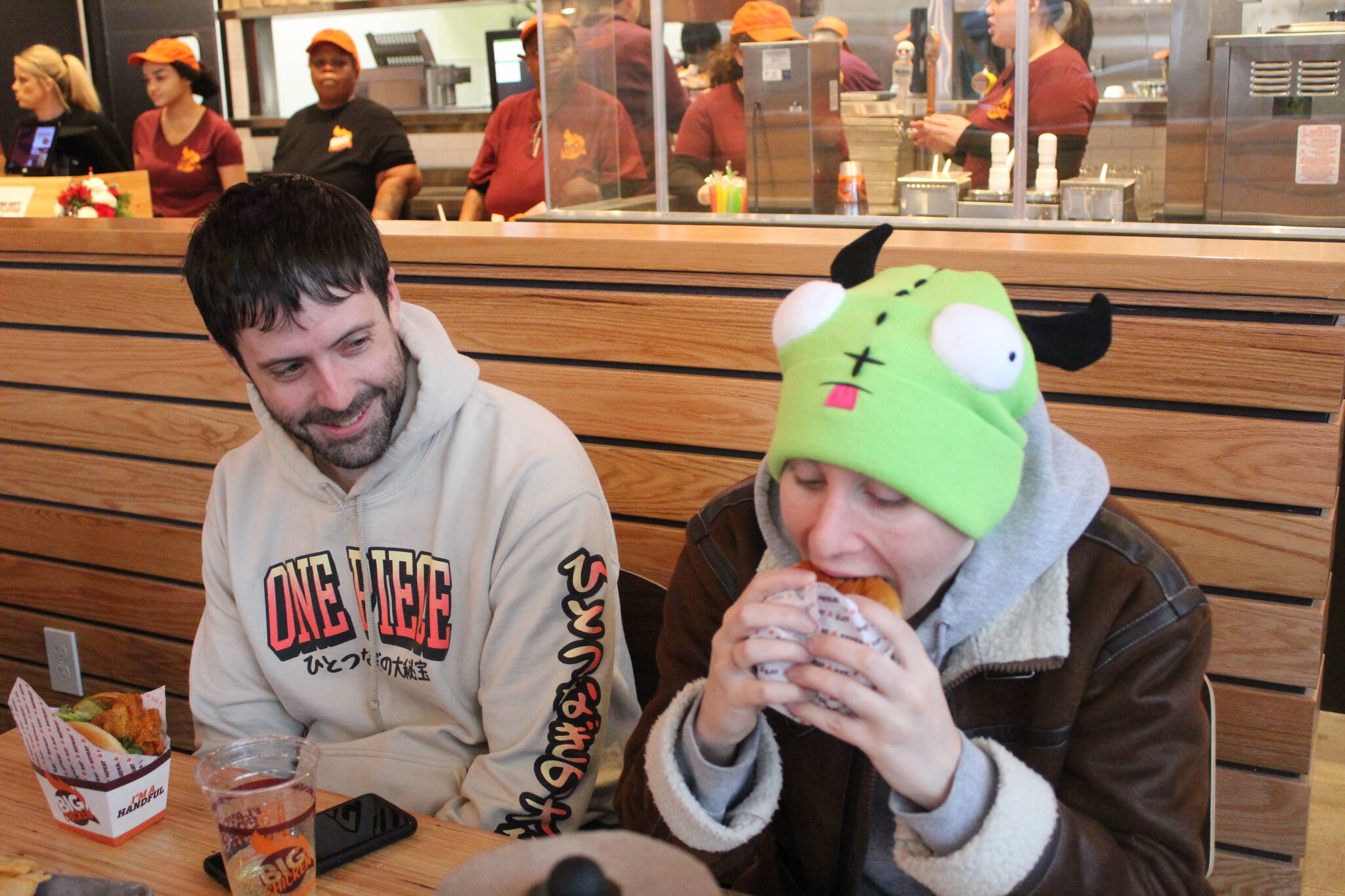 Rowan Cook, right, takes the very first bite of the first chicken sandwich ordered at the Renton Big Chicken as their partner Kyle Martin observes. Photo by Bailey Jo Josie/Sound Publishing.