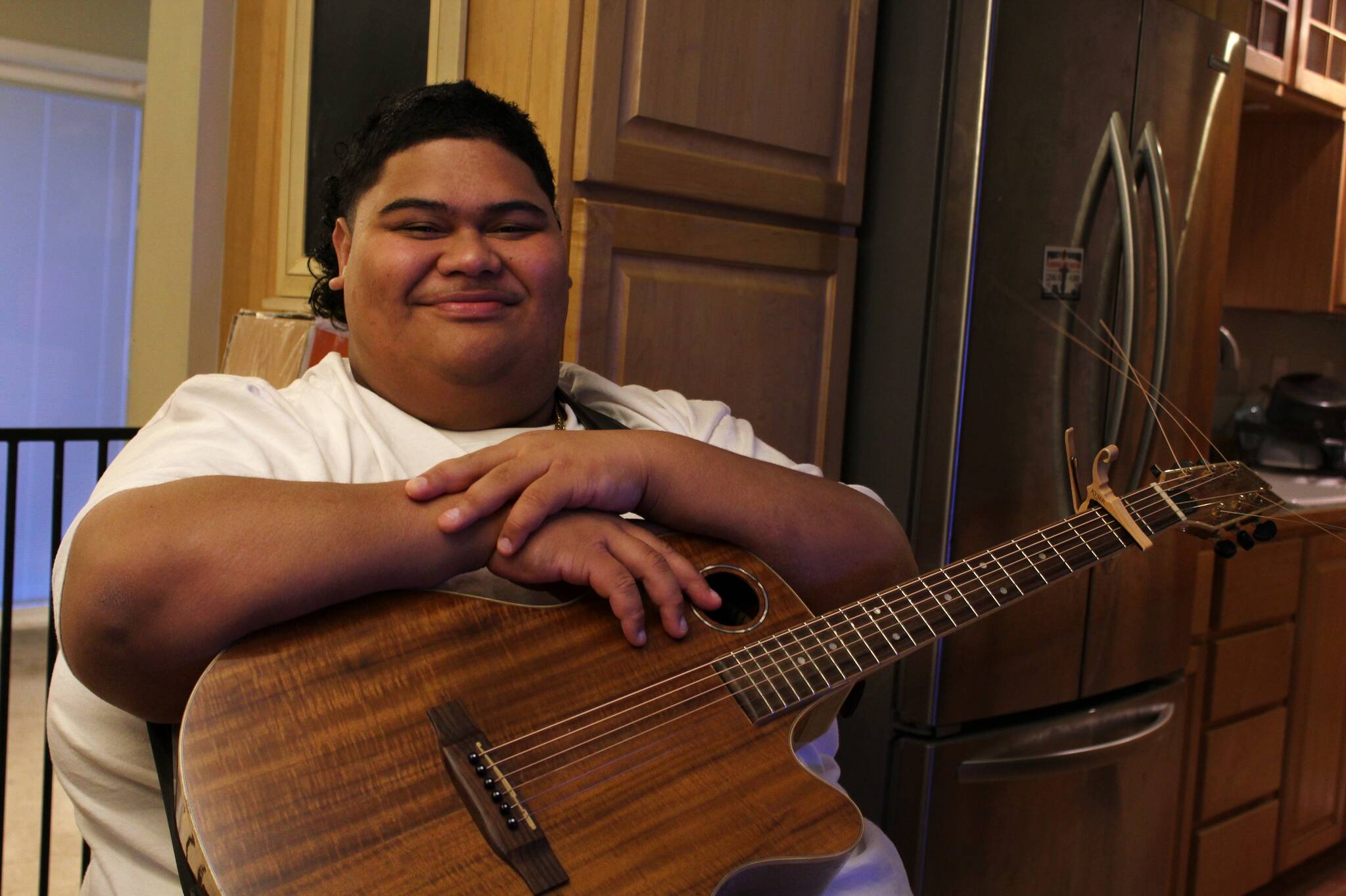 Decatur High School senior and “American Idol” contestant Iam Tongi sits at home on March 1. His father Rodney spent a bonus from his job as an electrician to buy Iam’s guitar. Alex Bruell, Sound Publishing