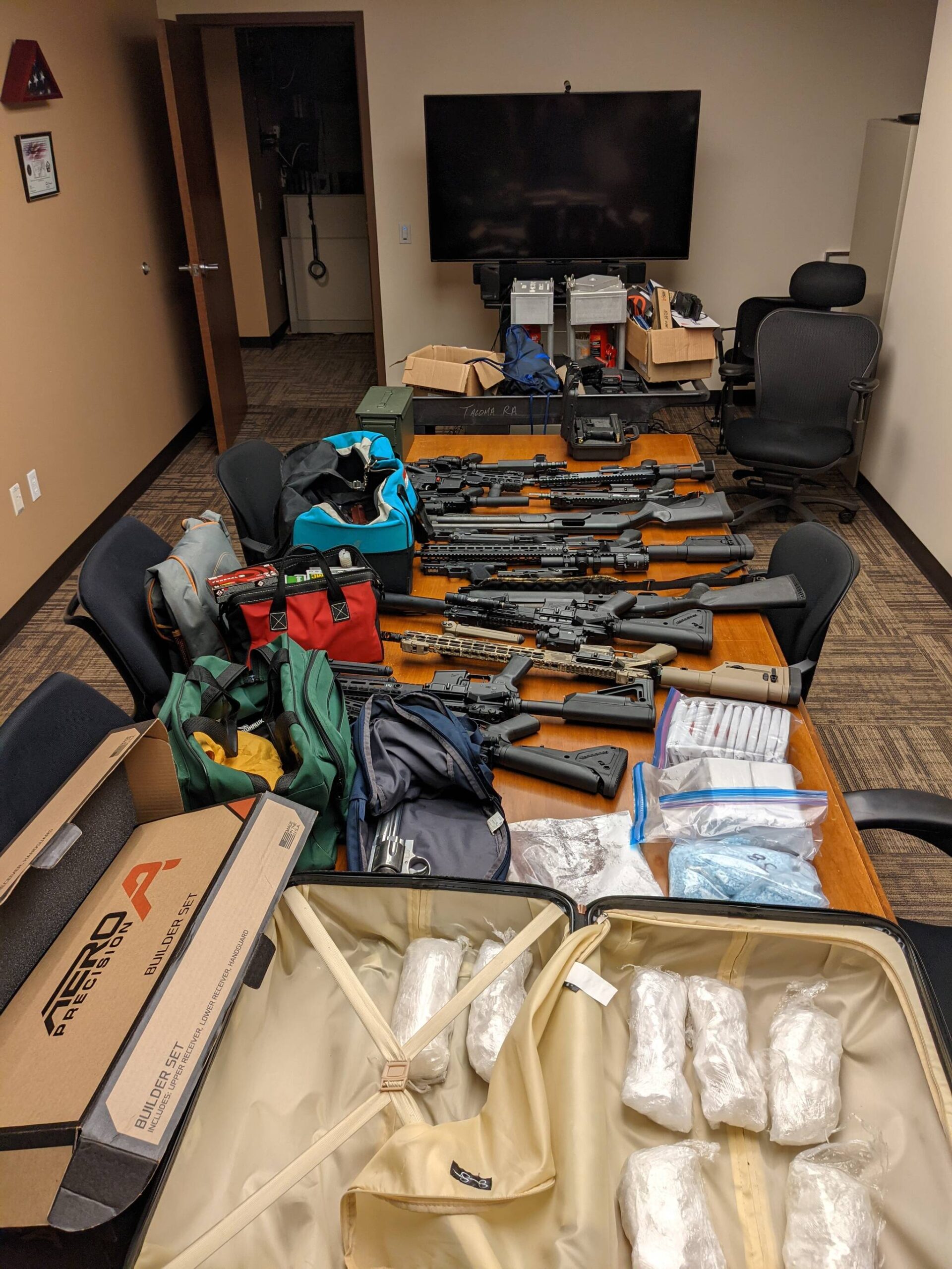 Law enforcement seized approximately 19 firearms, 3,372 grams of suspected methamphetamine, 1,322 grams of suspected fentanyl-laced pills, and over $210,000 in United States currency. (Courtesy of the Department of Justice)