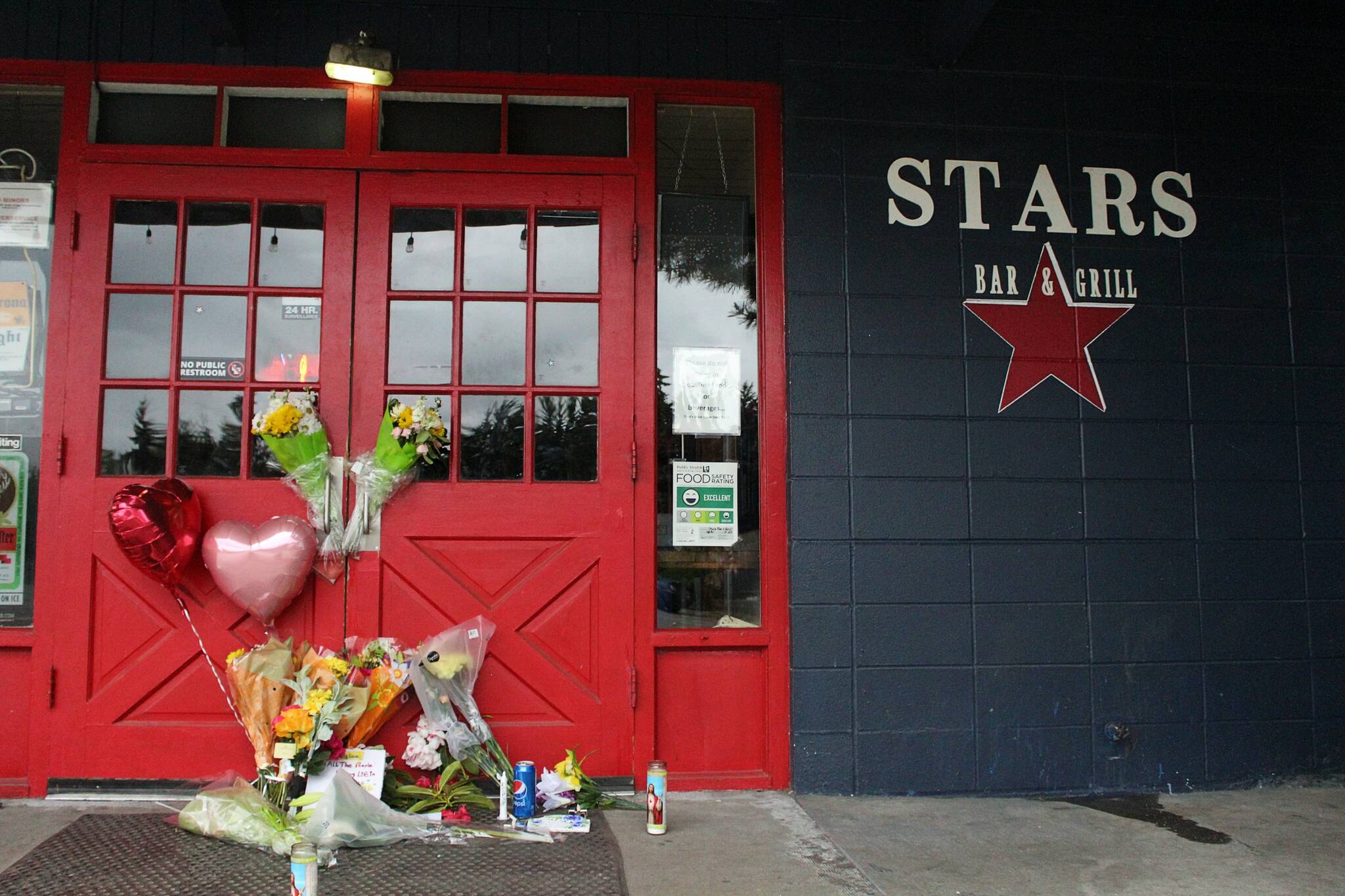 Flowers and candles are left by the door of the Stars Bar & Grill in Federal Way, where two employees were shot and killed early Sunday morning, May 21. A third man was shot and taken to a hospital. ALEX BRUELL, Sound Publishing