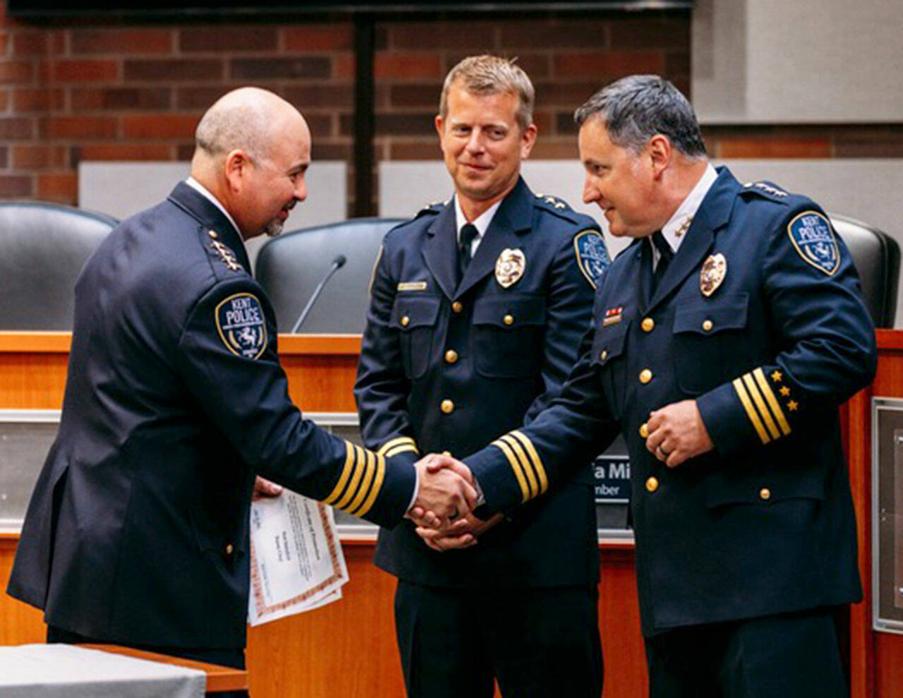 Kent Police Chief Rafael Padilla, left, congratulates new Deputy Chief Matt Stansfield as new Assistant Chief Andy Grove looks on during a promotion ceremony. COURTESY PHOTO, Kent Police