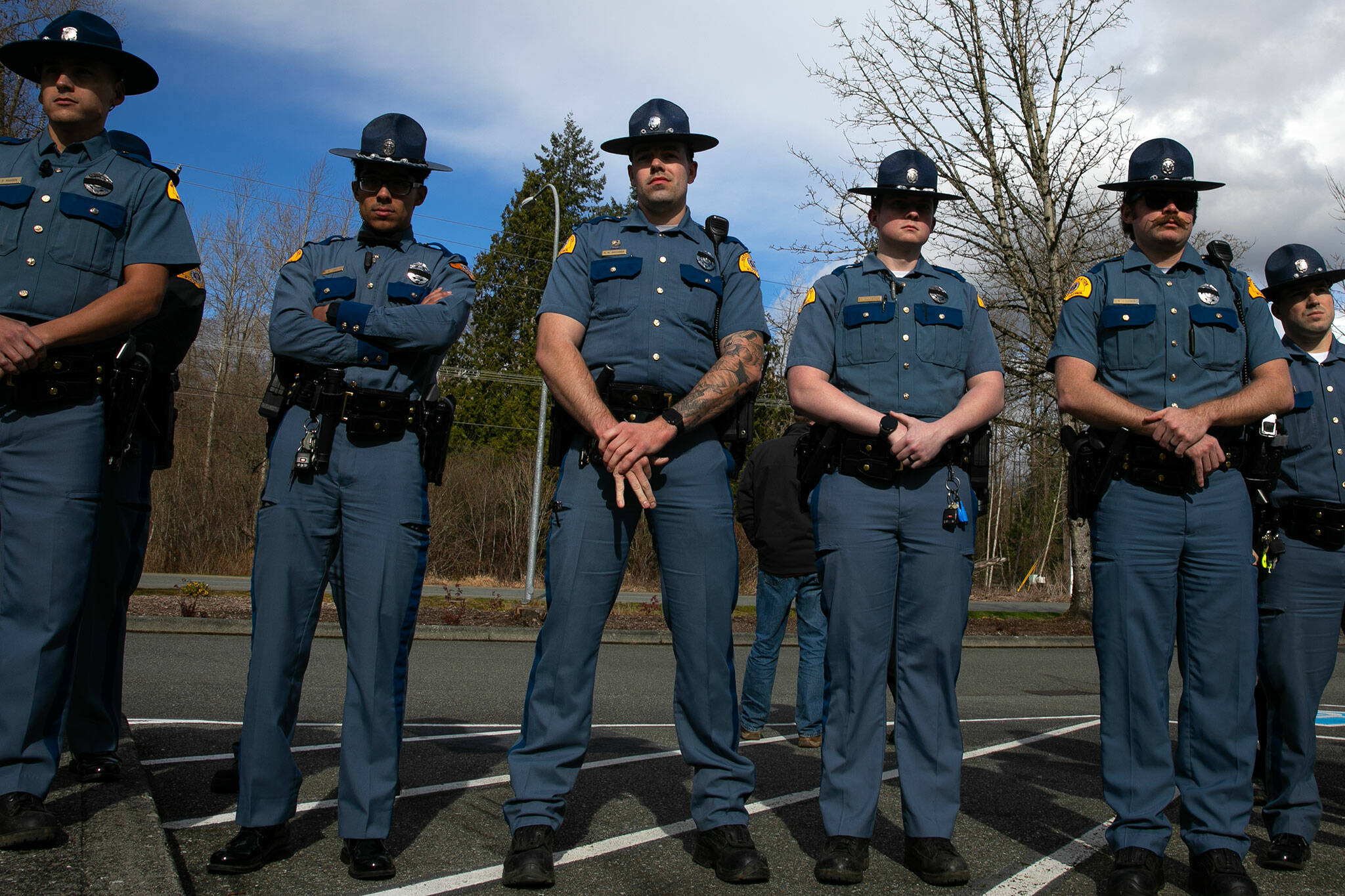 Troopers listen as Washington State Patrol Chief John Batiste addresses the media during a press conference regarding an overnight crash that killed trooper Chris Gadd on southbound I-5 Saturday, March 2, 2024, in Marysville, Washington. (Ryan Berry / The Herald)