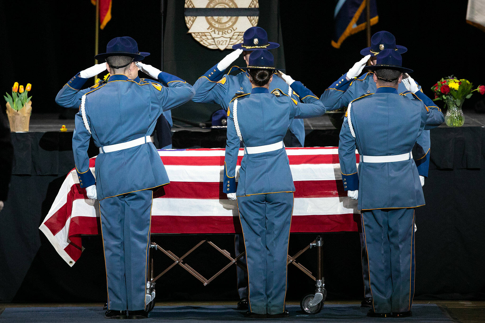 Members of Washington State patrol salute the casket of slain trooper Chris Gadd during a memorial cremony on Tuesday, March 12, 2024, at Angel of the Winds Arena in Everett, Washington. (Ryan Berry / The Herald)