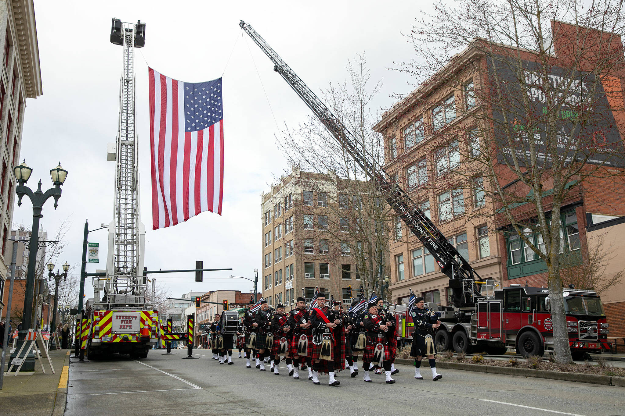 Bagpipes and drums lead a procession down Hewitt Avenue during a memorial for Washington State Trooper Chris Gadd on Tuesday, March 12, 2024, outside Angel of the Winds Arena in Everett, Washington. (Ryan Berry / The Herald)