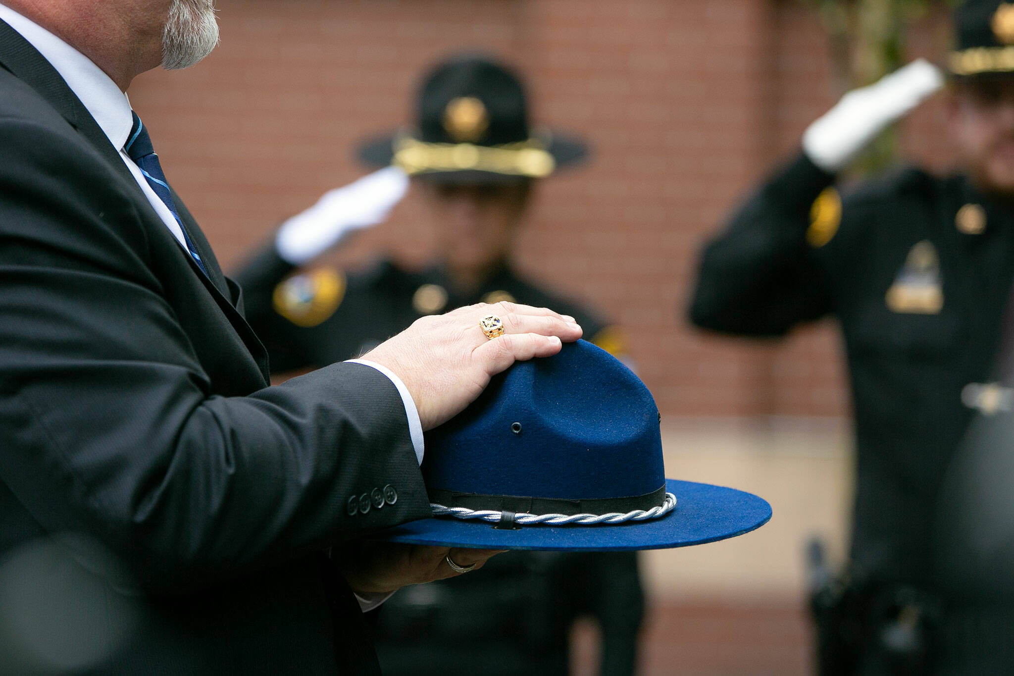 A trooper hat is carried behind Washington State Trooper Chris Gadd during a memorial on Tuesday, March 12, 2024, at Angel of the Winds Arena in Everett, Washington. (Ryan Berry / The Herald)