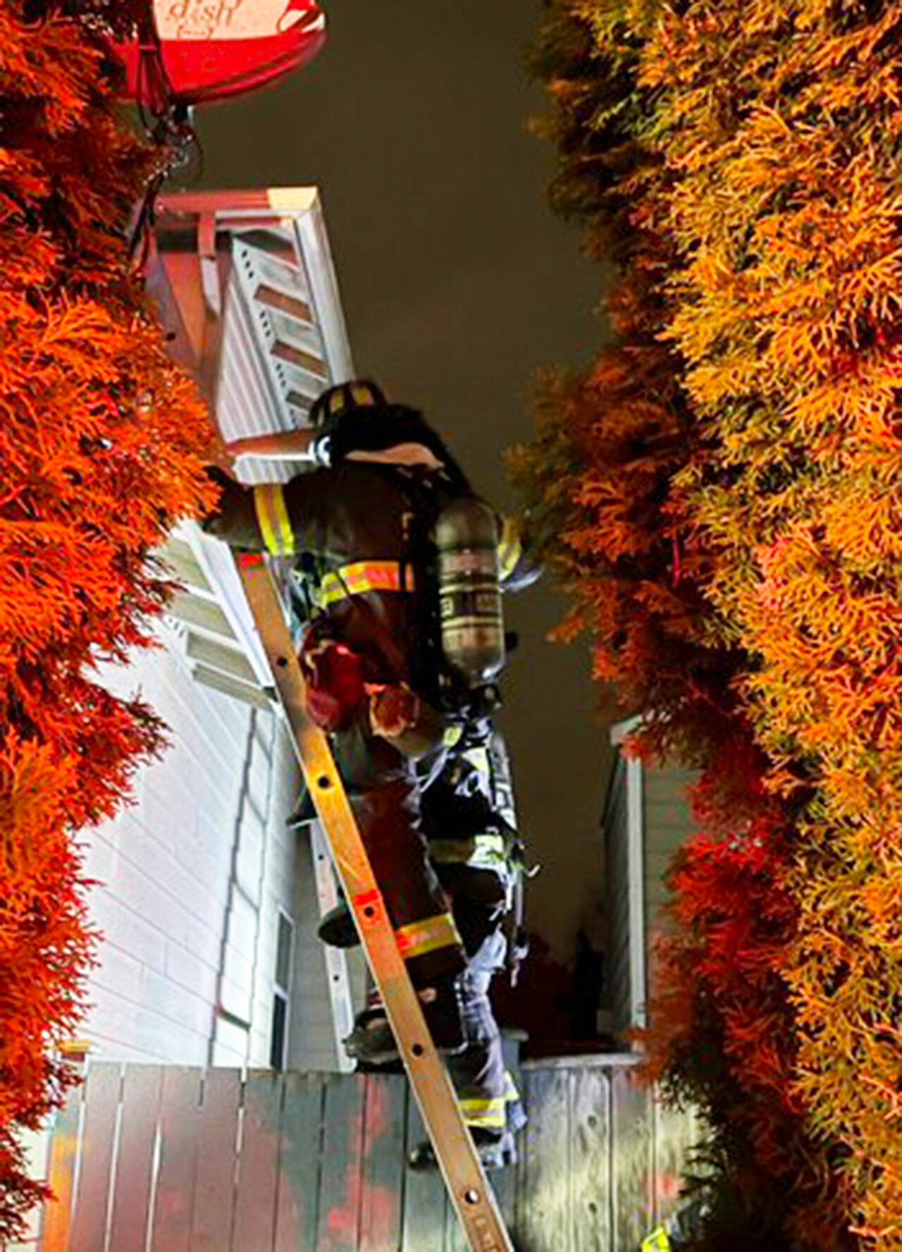 Firefighters scramble up ladders to rescue a male from the roof of a Kent house fire Tuesday night, March 19 in the 12400 block of SE 259th St. COURTESY PHOTO, Puget Sound Fire