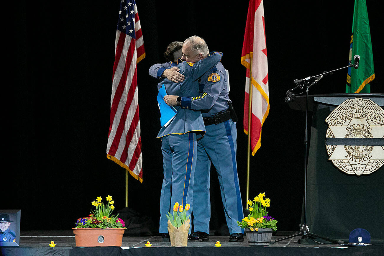 Captain Ron Mead and Corporal Alexis Robinson embrace during a memorial for Washington State Trooper Chris Gadd on Tuesday, March 12, 2024, at Angel of the Winds Arena in Everett, Washington. (Ryan Berry / The Herald)